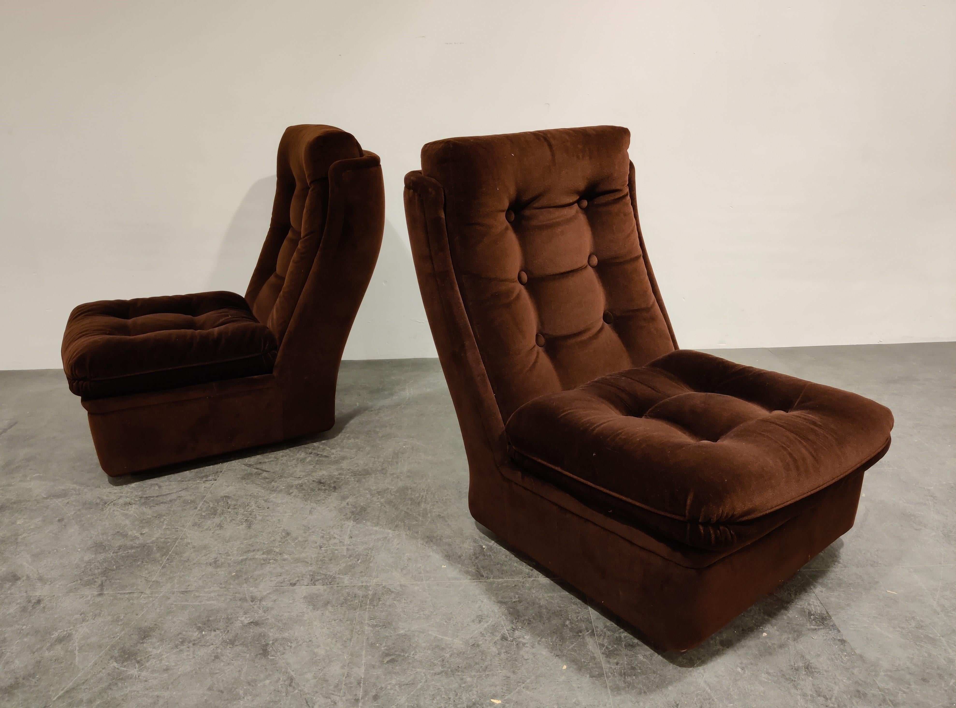 Pair of midcentury brown fabric lounge chairs on wheels.

The casters/wheels are hidden under the chair/ottoman

The chairs are very comfortable and come with their ottoman. 

Great vintage look.

1970s - France

Very good