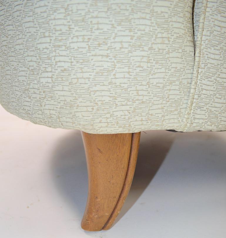 Mid  Century Hollywood Regency style upholstered in off white textured vinyl. Design after Robsjohn-Gibbings, manufacture attributed to John Widdicomb. Clean, original condition, upholstery shows minor cosmetic wear, normal and consistent with age.
