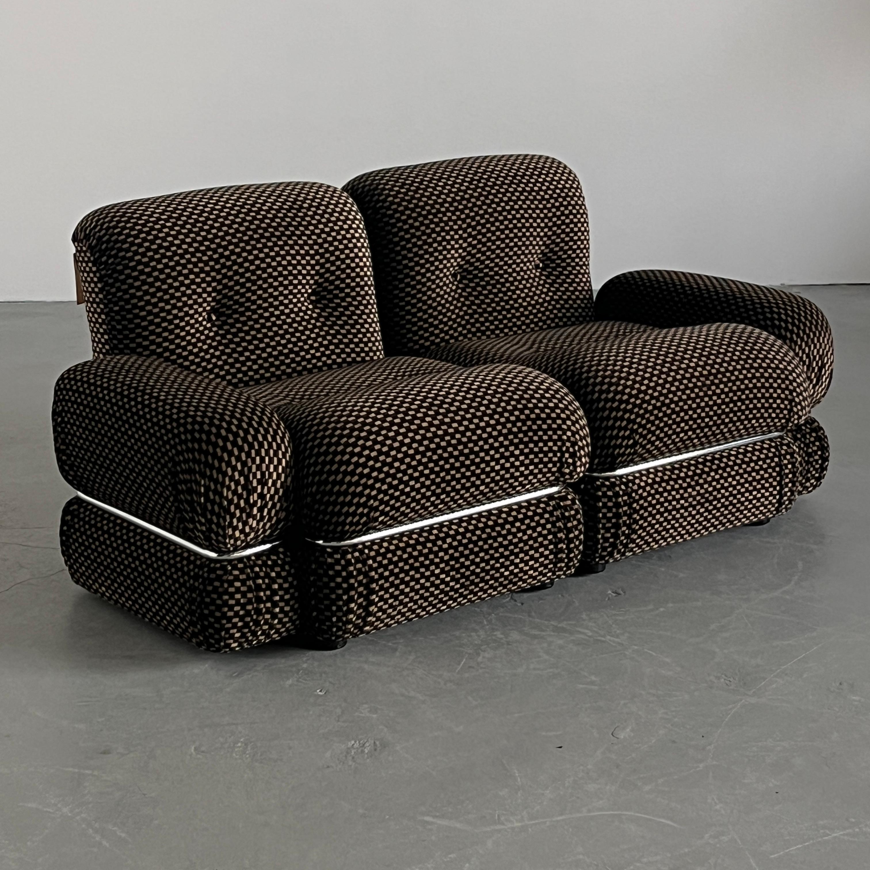 Causeuse italienne compacte et sculpturale des années 1970, dotée d'un revêtement en damier marron et beige d'origine et d'un bandeau en acier chromé.

Cette pièce présente des lignes à la fois ludiques et épurées, typiques des sièges modernistes