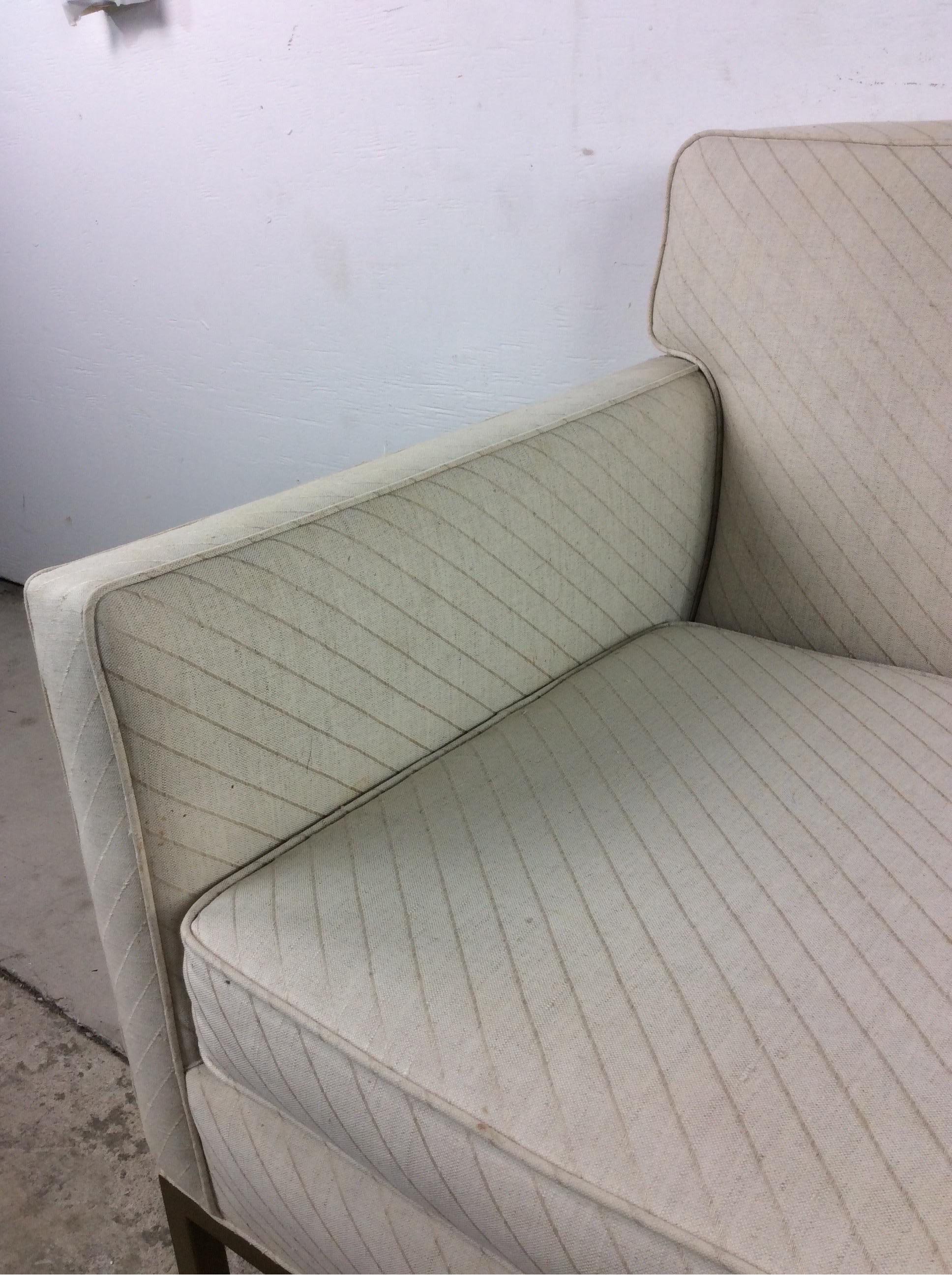 Dieser moderne Sessel aus der Mitte des Jahrhunderts hat eine Vintage-Polsterung, zwei abnehmbare Kissen und einzigartige Beine und Sockel mit Messingakzenten. 

Ein Dreisitzersofa ist separat erhältlich.