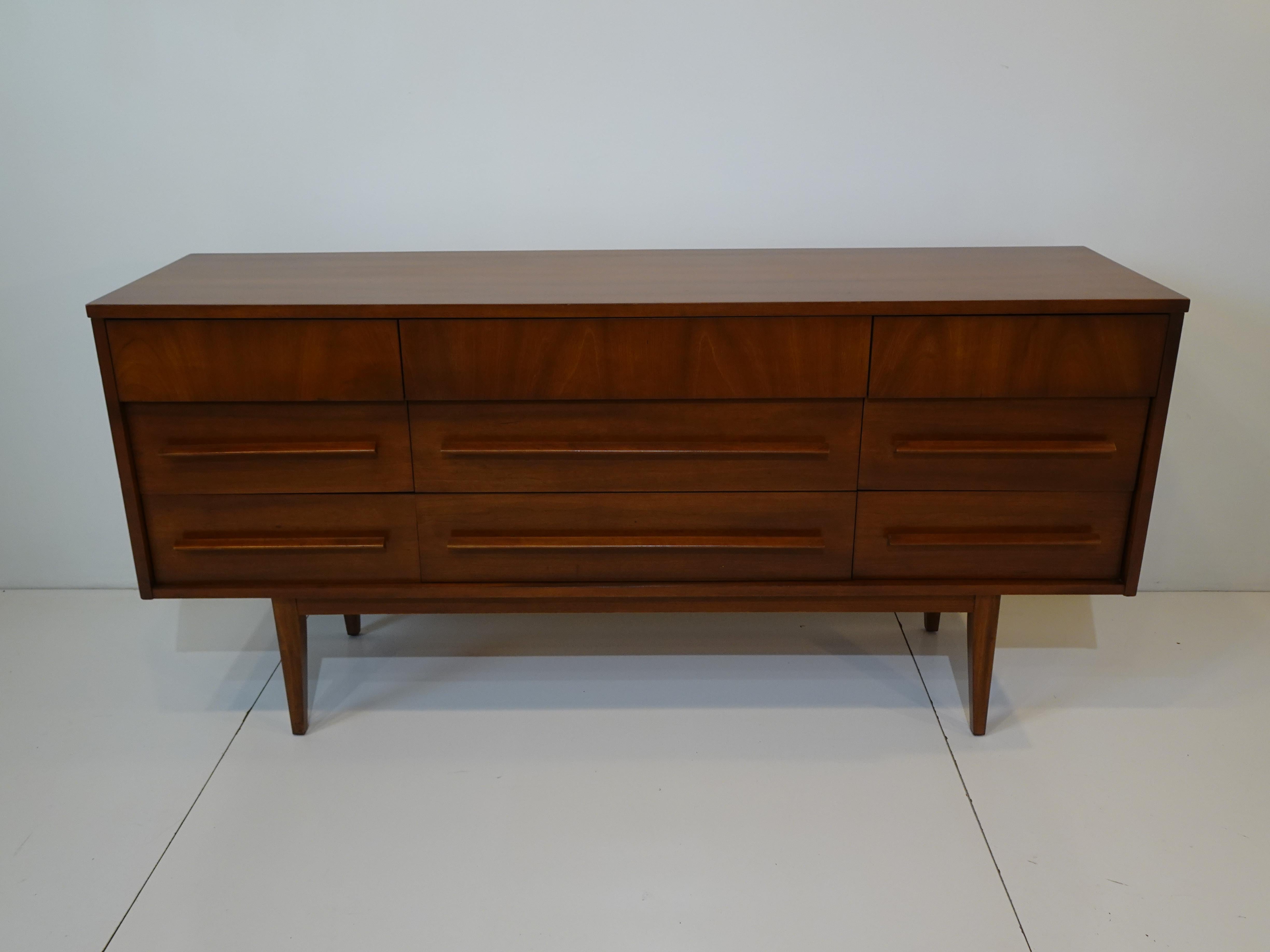 A dark walnut mid century dresser with long matching streamline pull handles with three upper slim styled drawers and six lower drawers . The piece has a low profile which is perfect giving the chest a nice clean design that can be used as a