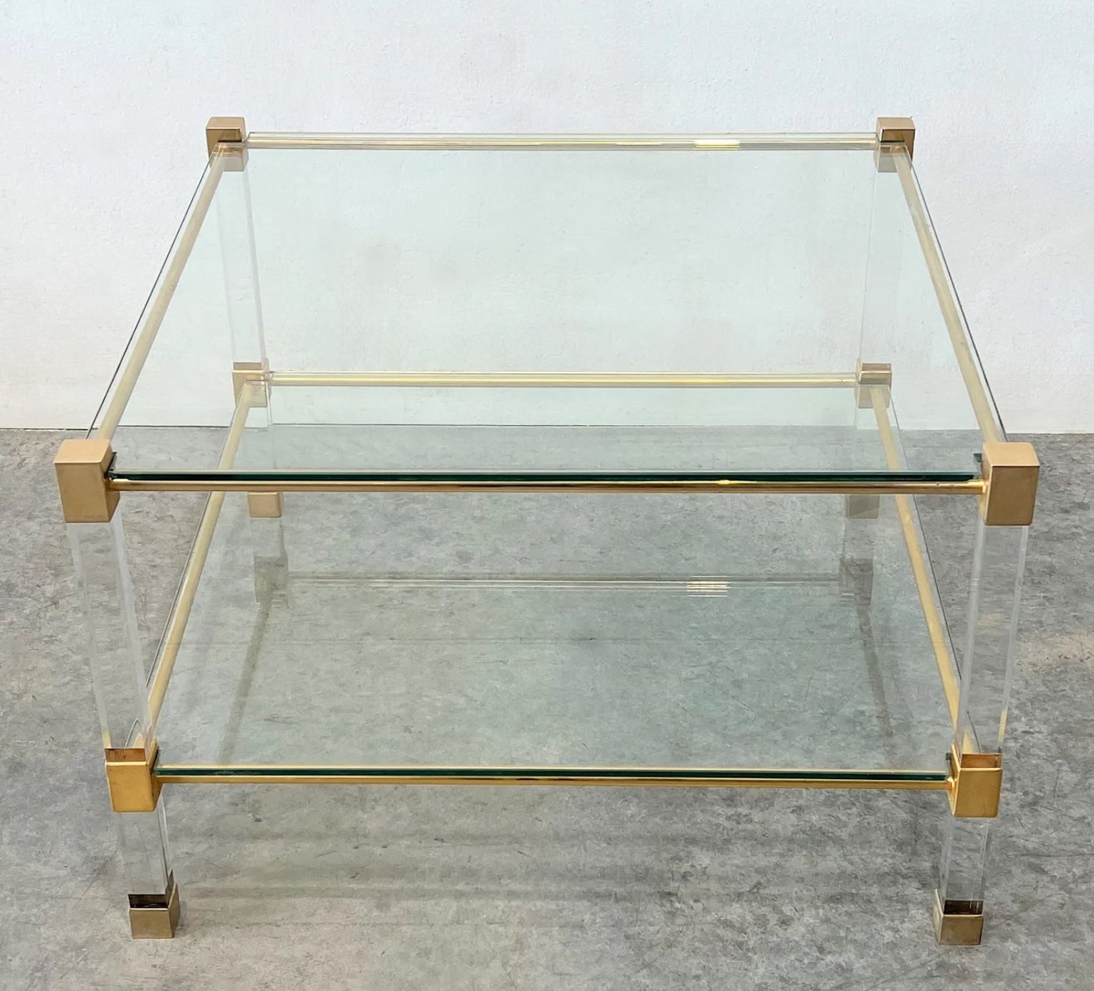 Table basse carrée à pieds en lucite et laiton du milieu du siècle dernier avec deux étagères en verre.  

La table est en bon état, avec une usure minimale correspondant à son âge. 

Dimensions :
Hauteur : 17 3/4