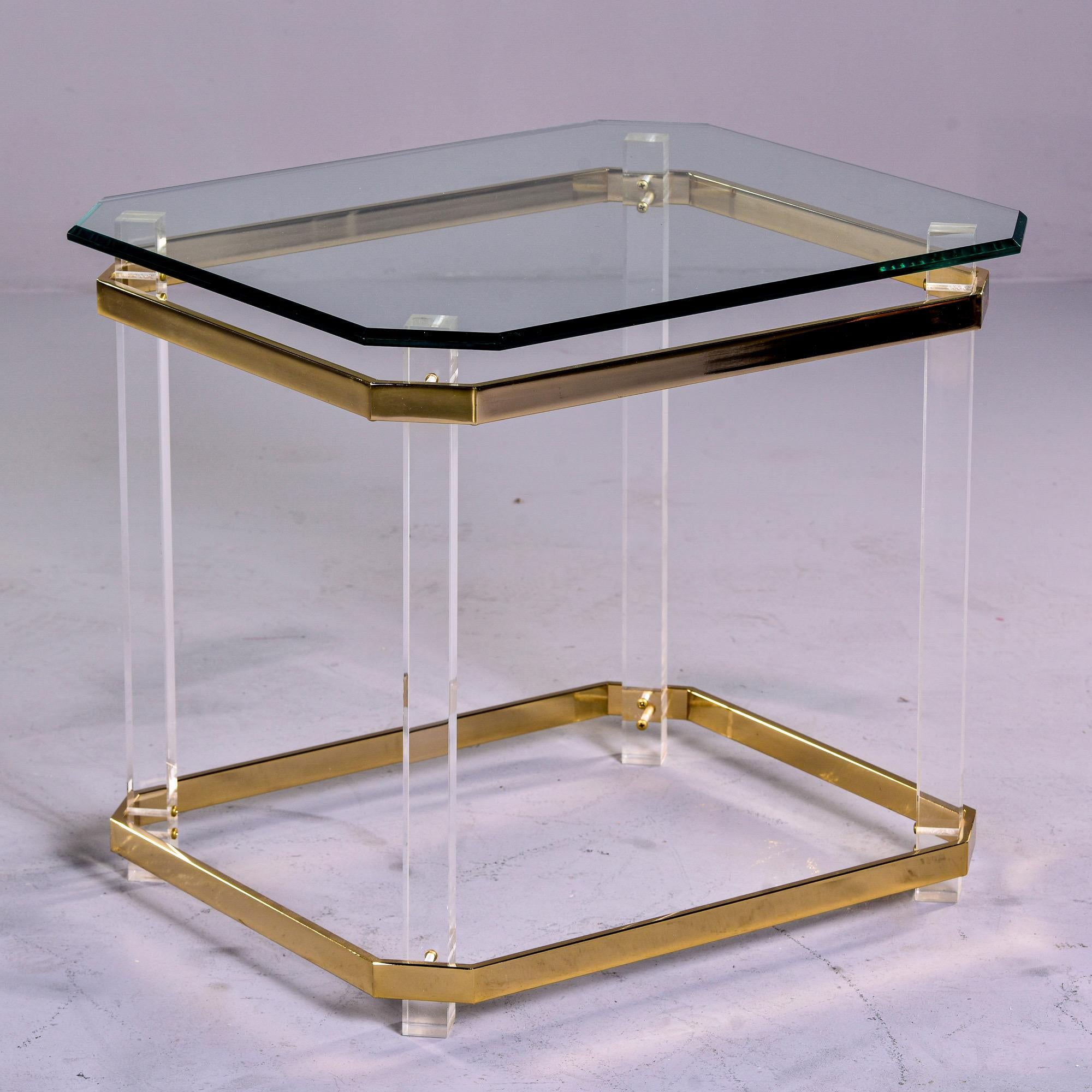 Circa 1970s side or end table with beveled edge glass top, clear lucite legs and flat brass plated banding at base and apron. Excellent vintage condition with very little visible wear.