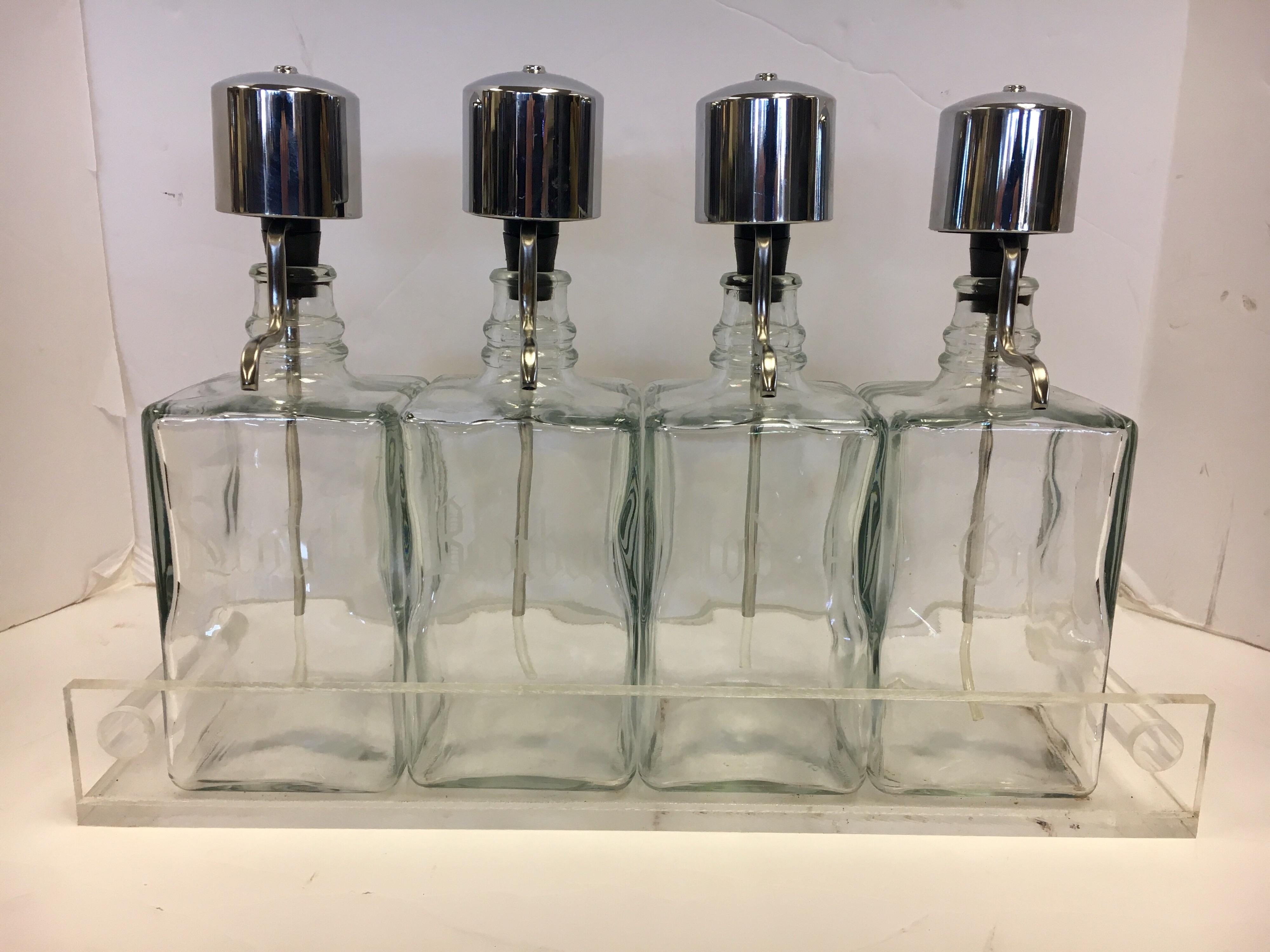 Rare midcentury barware with four decanters, each hallmarked either Scotch, Bourbon, Vodka or Gin and all with rare pump mechanism for the perfect pour. They are glass but sit in a Lucite tray which is magnificent.