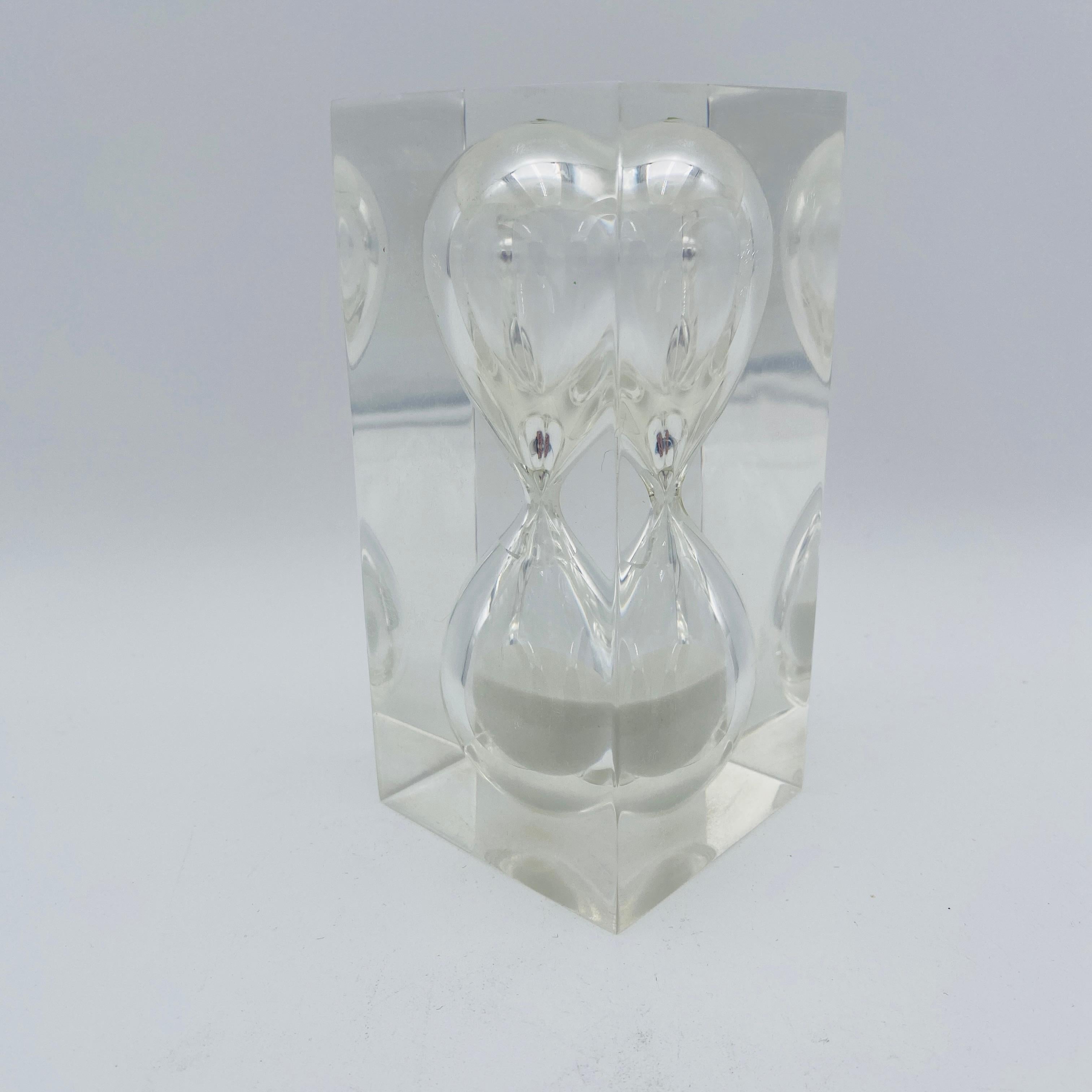Si tratta di una scultura a clessidra in lucite della metà del secolo scorso, realizzata negli anni '60 circa. Si tratta di una clessidra della durata di un'ora in cui la sabbia si deposita lentamente sul fondo. Sarebbe perfetto in cucina o su una