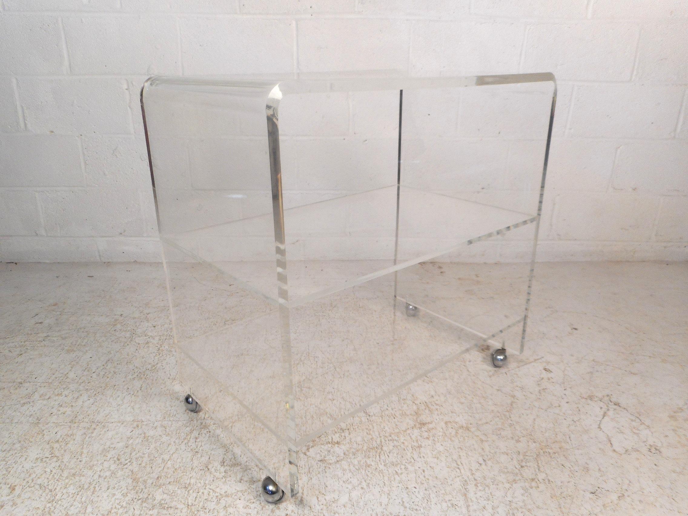 Stylish midcentury Lucite shelf unit on castors. Two shelves within the unit provide storage space. A convenient and dynamic storage/serving solution sure to be a great addition to any modern interior. Please confirm item location with dealer (NJ or