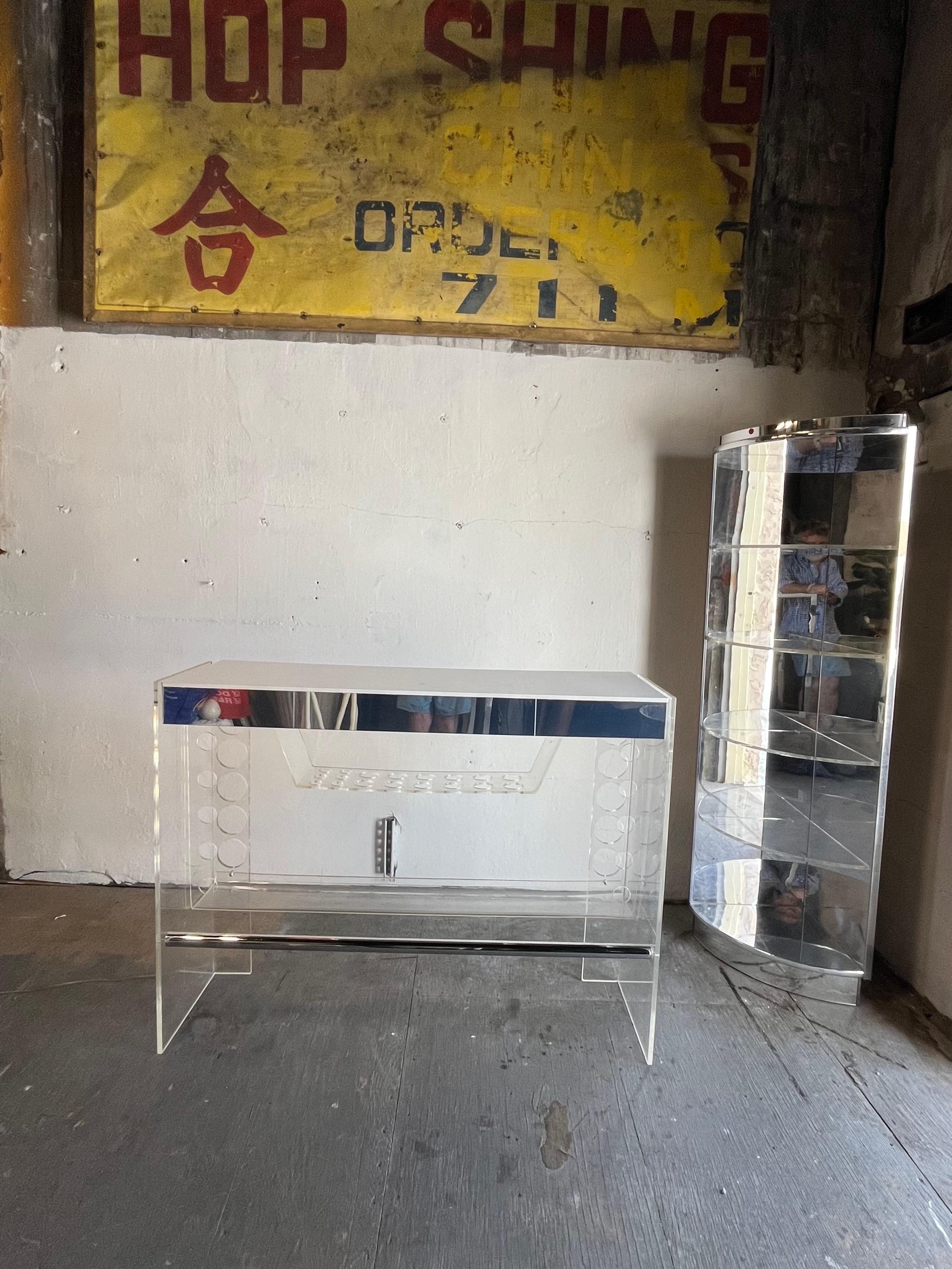 Fabulous mid century lucite bar and corner shelf by Luigi Bardini for Hill Manufacturing. Tubular chrome foot rail and rear mirrored accent. Drawer for storage as well as bottle and glass holders. Underneath light for illumination. Rare to find