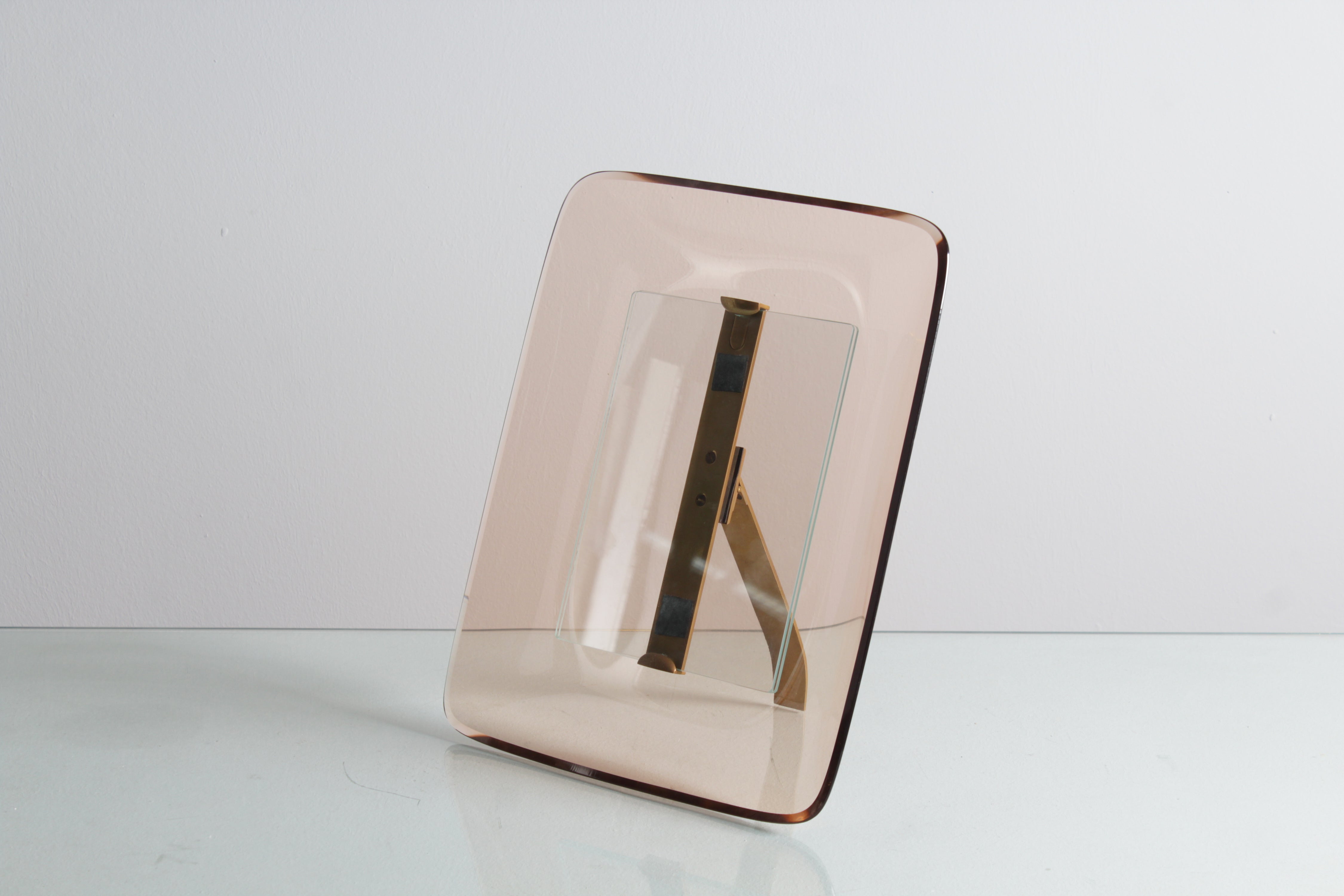 Wonderful portrait frame with pink curved crystal frame of rectangular shape with rounded edges, brass support. Designed by Max Ingrand for Fontana Arte, Italian production since 1939. Wear consistent with age and use.
Depth of the portrait frame