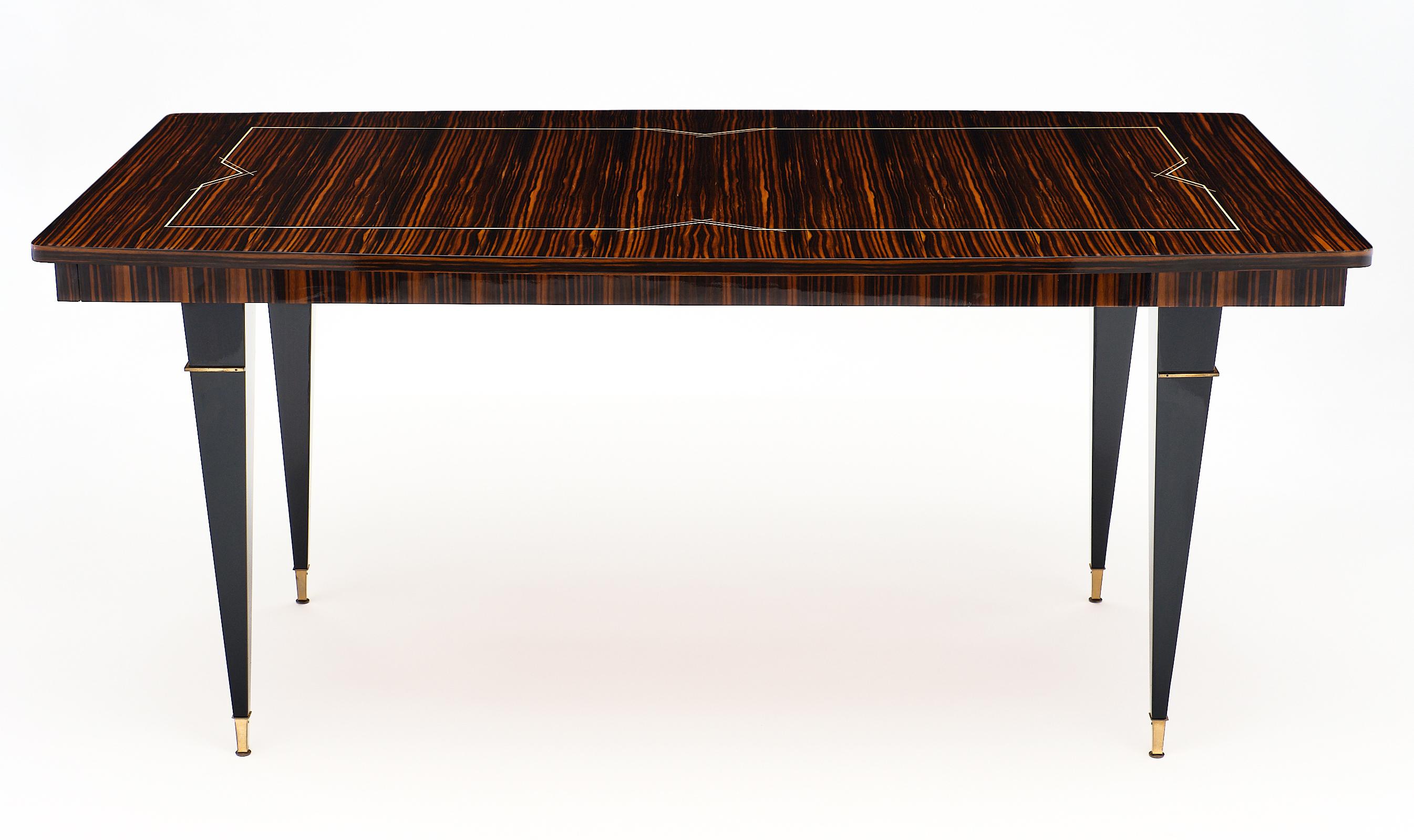 Macassar midcentury dining table from Lyon, France. This piece has a beautiful inlay and lovely tapered legs. We love the exotic wood and strong presence of this piece.