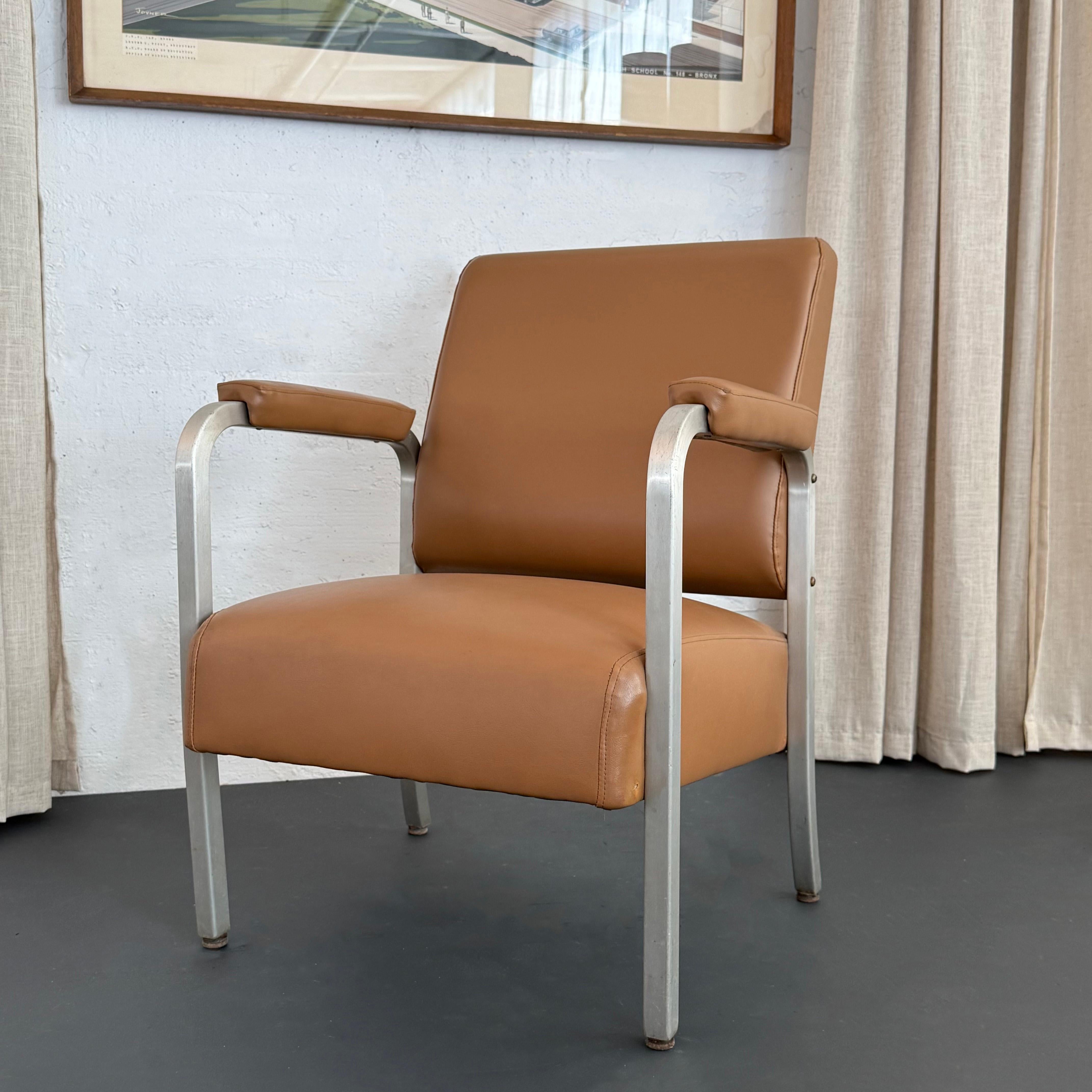 Dieser Sessel aus der Mitte des Jahrhunderts hat einen eleganten Rahmen aus gebürstetem Aluminium in einer kantigen Silhouette mit Sitzfläche, Rückenlehne und Armlehnen, die neu mit einem kräftigen, camelfarbenen Leder bezogen sind. Der Stuhl ist