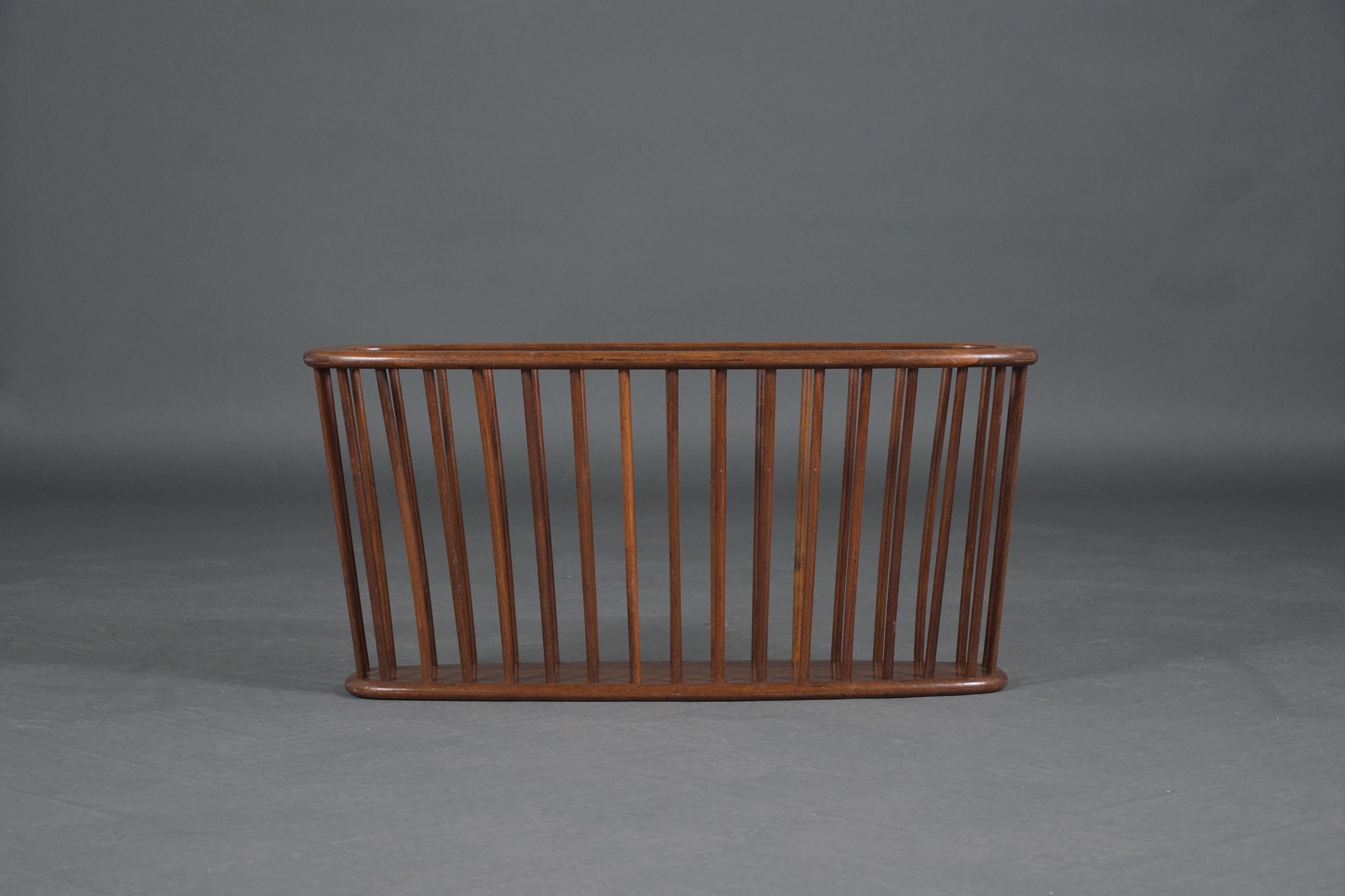 An extraordinary 1950s Arthur Umanoff magazine rack that is in good condition and has been restored by our team of craftsmen. This piece is hand-crafted out of walnut wood features elegant dark walnut color with lacquer finish and an oval shape
