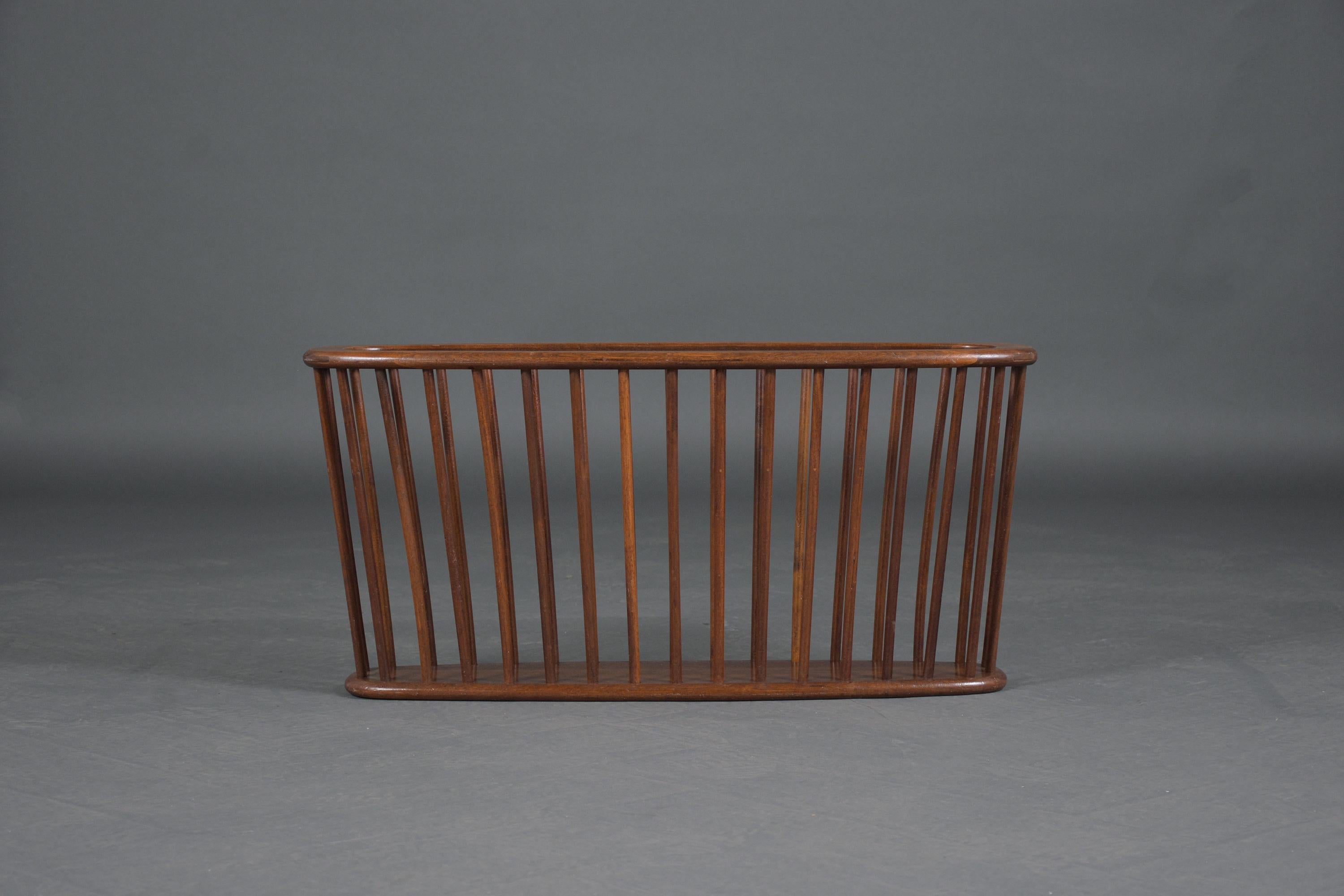 An extraordinary 1950s Arthur Umanoff magazine rack that is in good condition and has been restored by our team of craftsmen. This piece is hand-crafted out of walnut wood features elegant dark walnut color with lacquer finish and an oval shape
