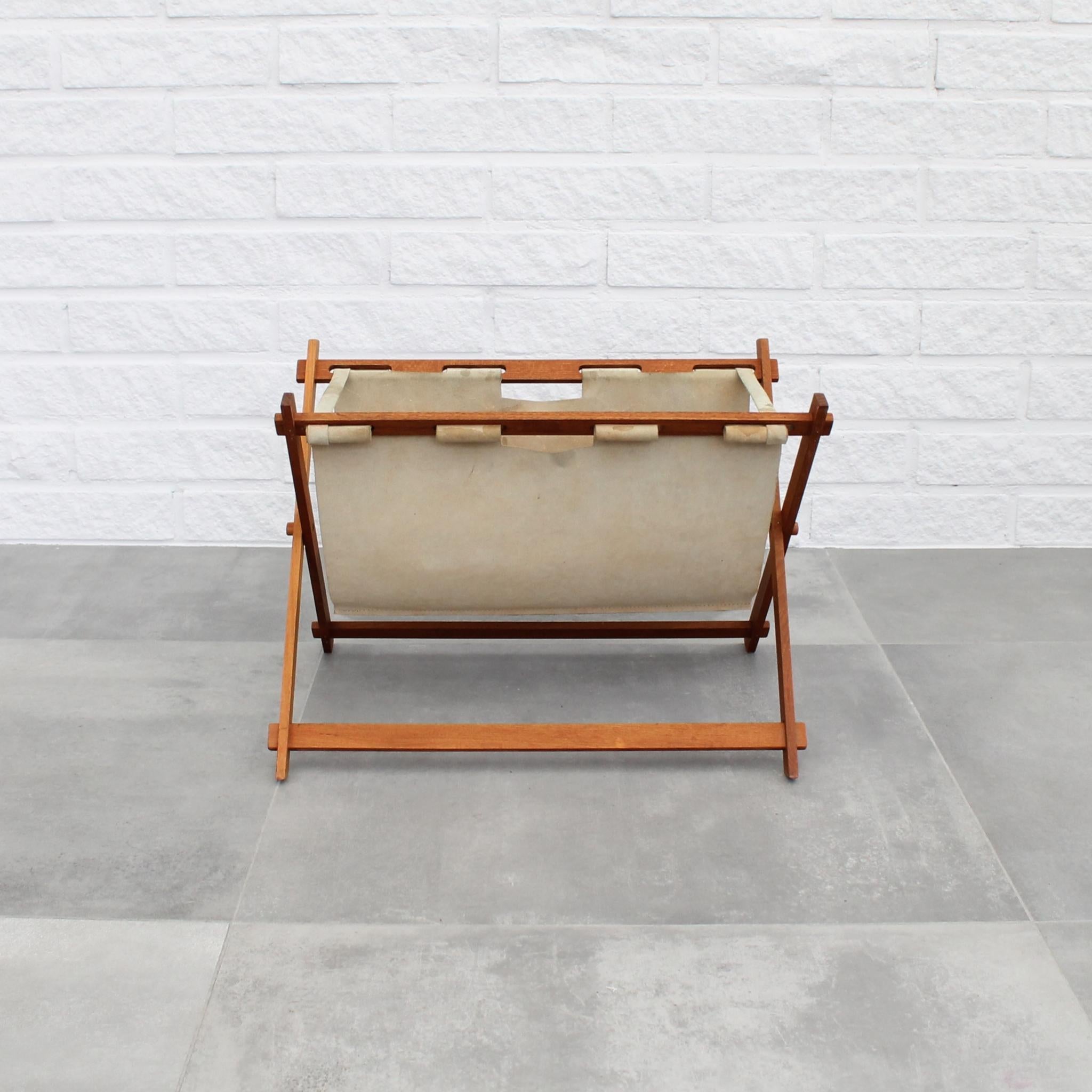 Swedish mid-century magazine rack crafted from solid teak, featuring suede leather. Its foldable design allows for convenient storage and transport. Notably, the sling leather is secured in place by wooden dowels, giving the magazine rack its