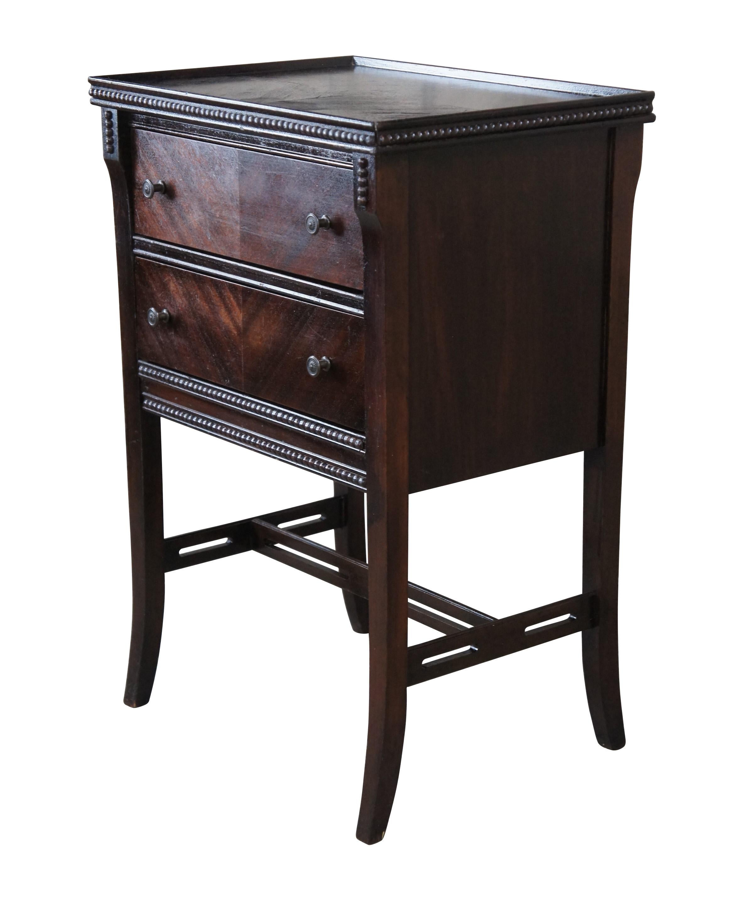 A lovely mid century mahogany nightstand.  Features a rectangular frame with two matchbook V grain drawers, an inset top and beaded trim.  The table is raised over flared legs with pierced stretchers.  

Dimensions:
19