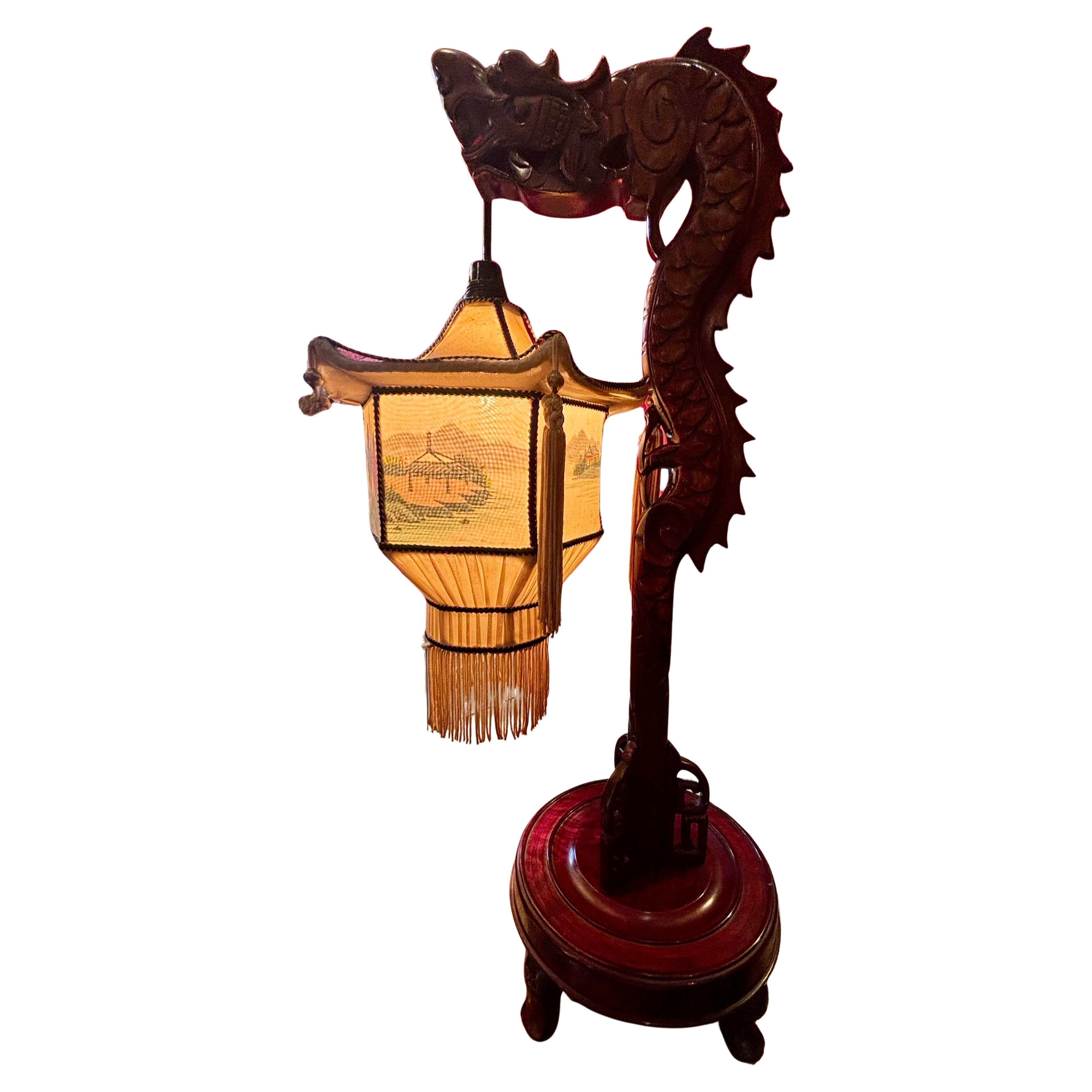 Un'insolita e stravagante lampada cinese della metà del secolo composta da  un drago in piedi in legno intagliato su una base circolare  piedistallo in legno con piedi a toupet che funge da lampada  stand con un  lampada a pagoda in tessuto con