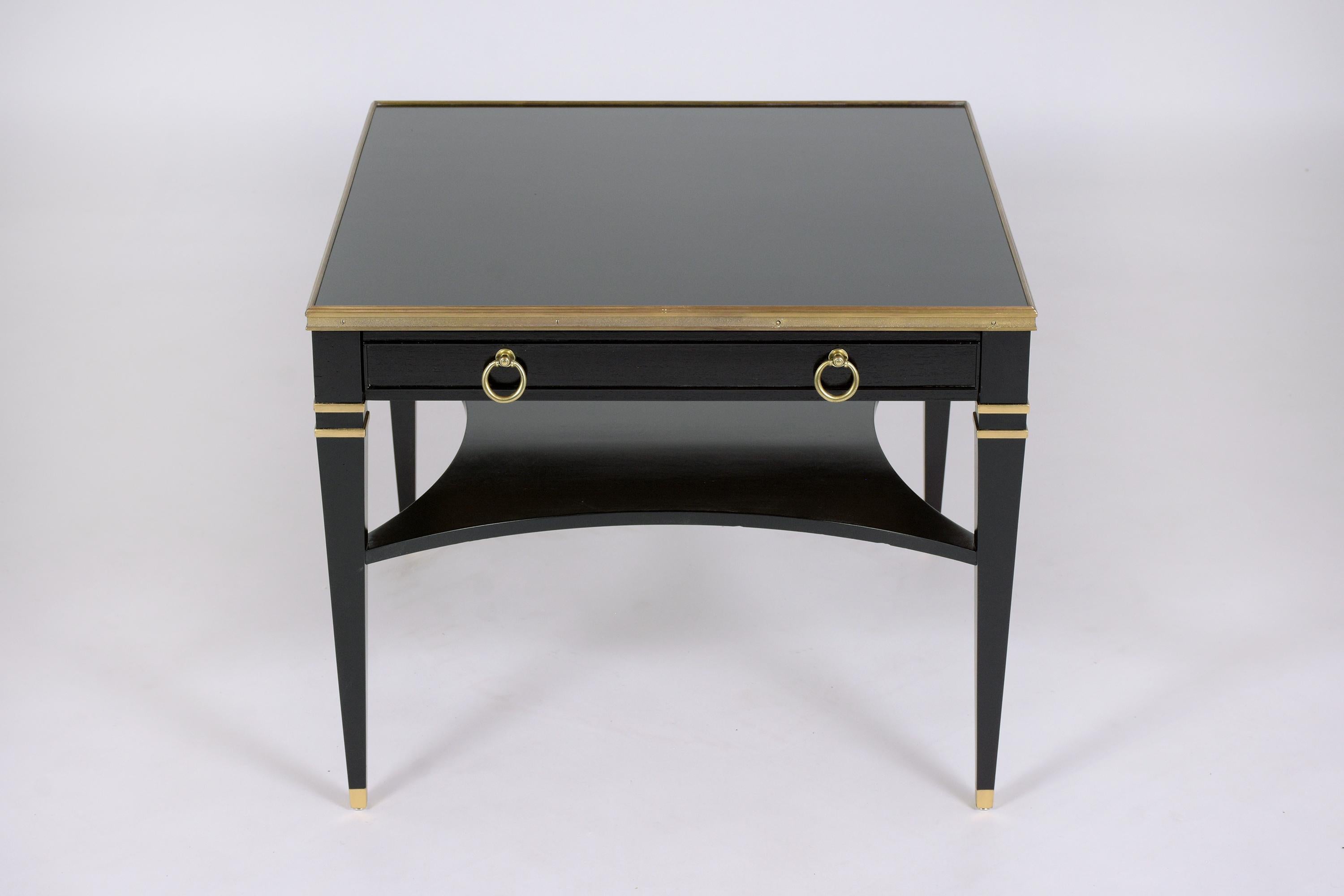 An extraordinary Baker's coffee-table hand-crafted out of mahogany wood in great condition and completed restored by our craftsmen team. This fabulous end table features an elegant ebonized color accentuated with giltwood molding details, a square