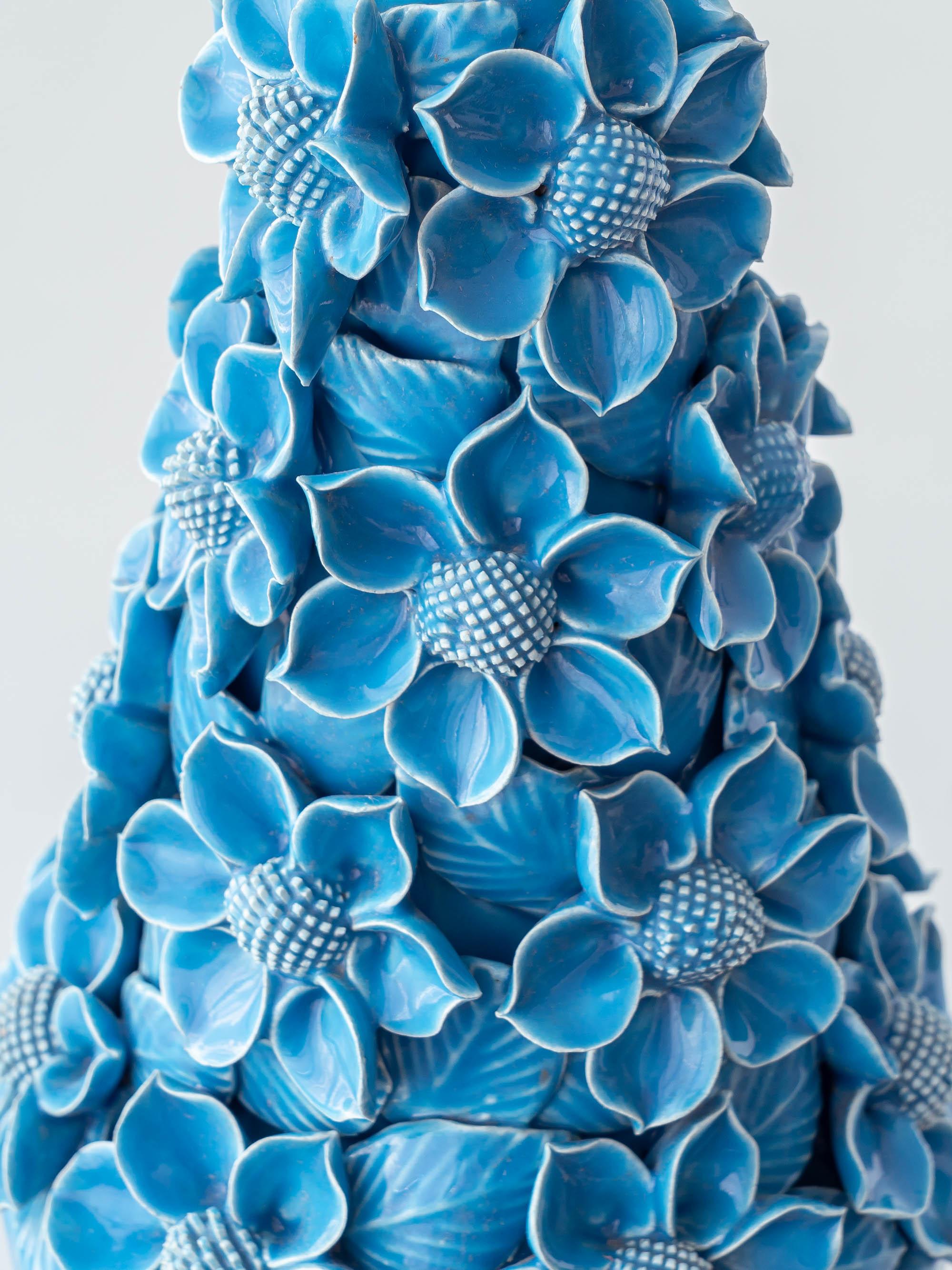 Sculpturale et saturée, cette lampe de table Manises du milieu du siècle présente un cône de fleurs exubérantes en céramique, sculptées et appliquées à la main, dans une glaçure turquoise brillante, s'élevant d'un pied d'urne sur un socle doré. Les