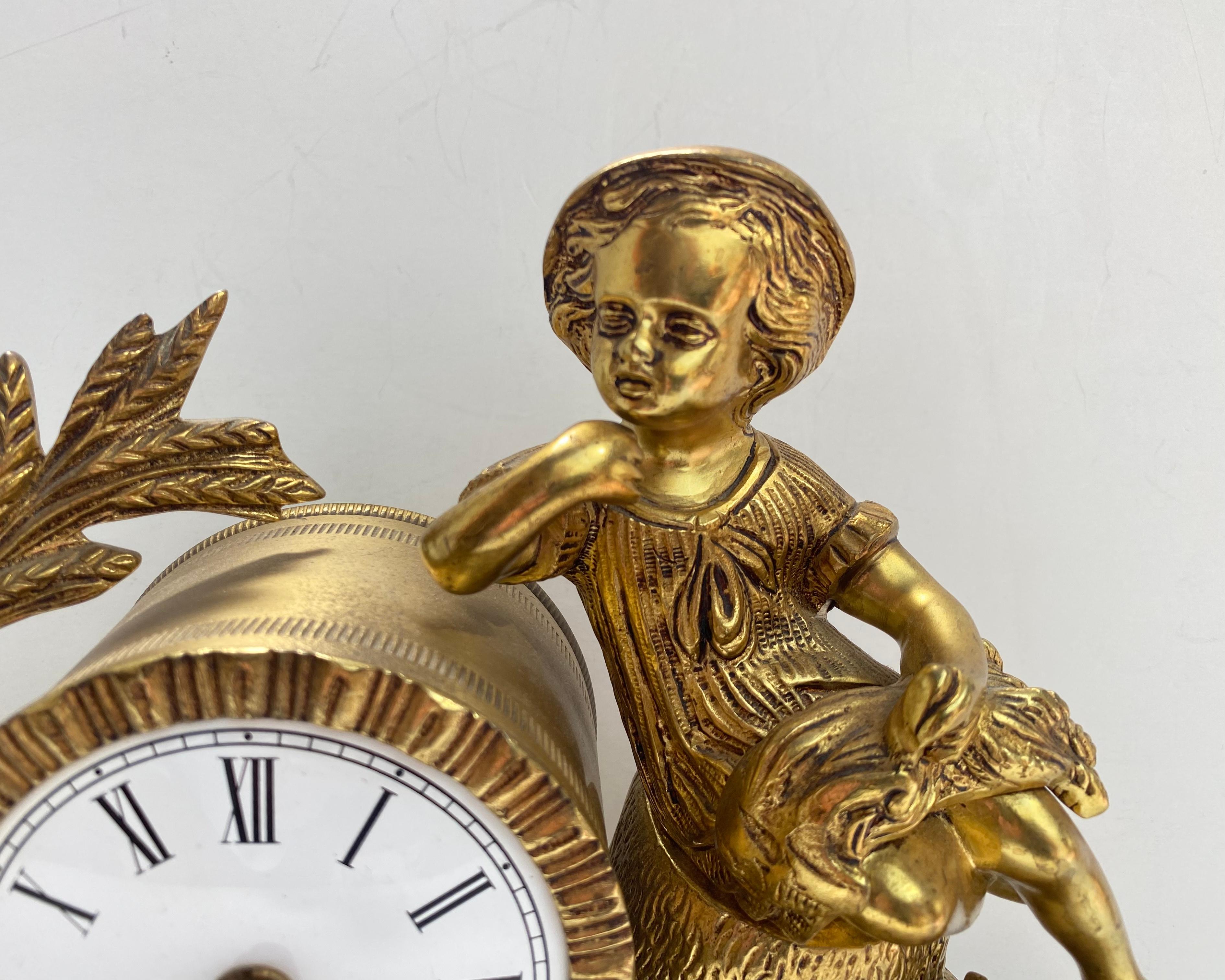 Victorian style gilded spelter figural mantel clock from the Mid -20th century.
Featuring a well-cast bronze figure of a young boy / child dressed in Victorian era garment, sheaves of wheat and scythe, heavily decorated Rocaille style design,