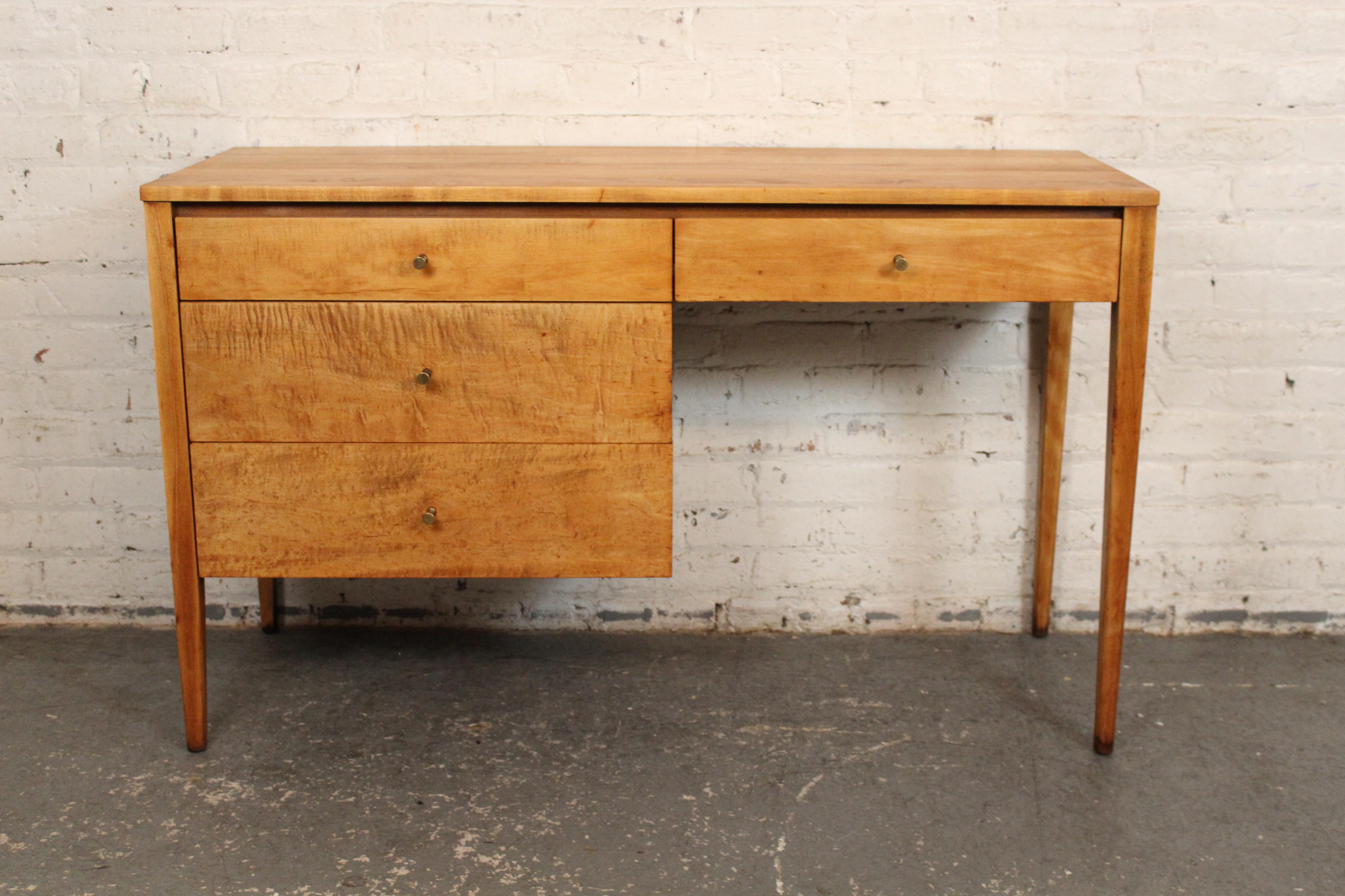 This mid-century desk was designed by American furniture maker Paul McCobb for Winchendon. Featuring blonde maple wood throughout and accenting brass pulls. Four total drawers and long tapered legs finish this simple yet modern design.
Please