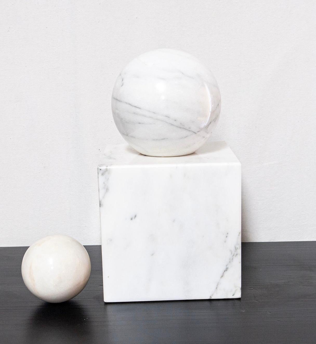 Viene presentato un solido piedistallo quadrato in marmo di metà secolo con due dimensioni di sfere rotonde in marmo.  La sfera più grande ha un fondo appiattito per poter essere appoggiata sul piedistallo o accanto ad esso.  La sfera più piccola è