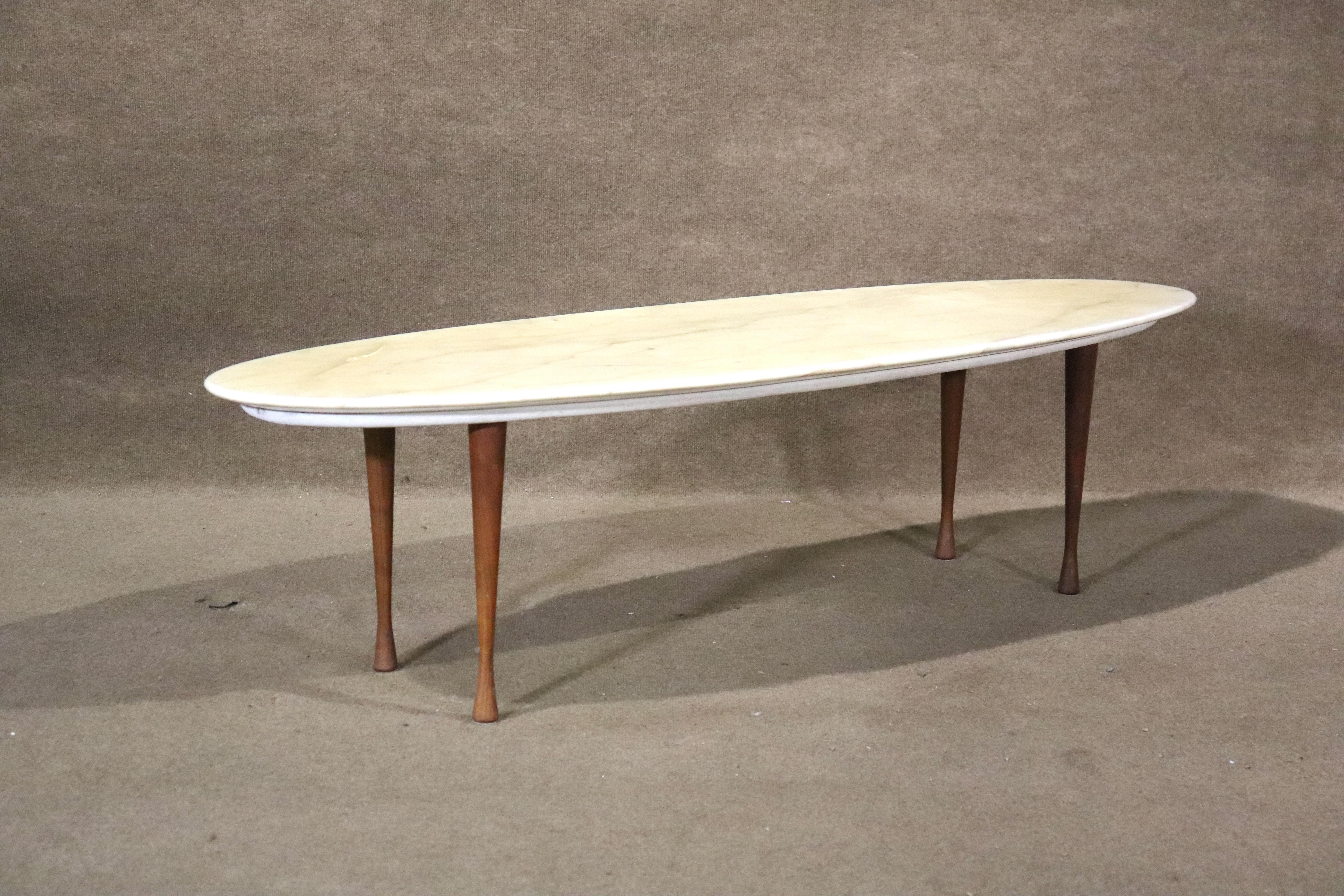 Table basse ovale de 5 pieds de long avec un plateau marbré blanc sur un cadre en bois avec des pieds effilés. Forme simple de planche de surf avec un sommet ovale brillant.
Veuillez confirmer le lieu NY ou NJ