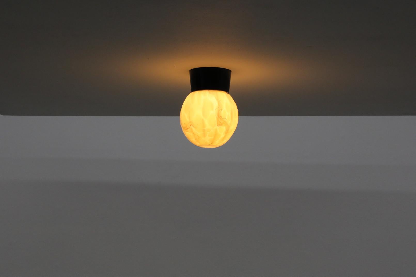 1960s flush mount ribbed glass globe sconce for ceiling or wall mounting with green and yellow marbled design on a black Bakelite base. In original condition with age appropriate wear. Other similar sconces available, listed separately, please