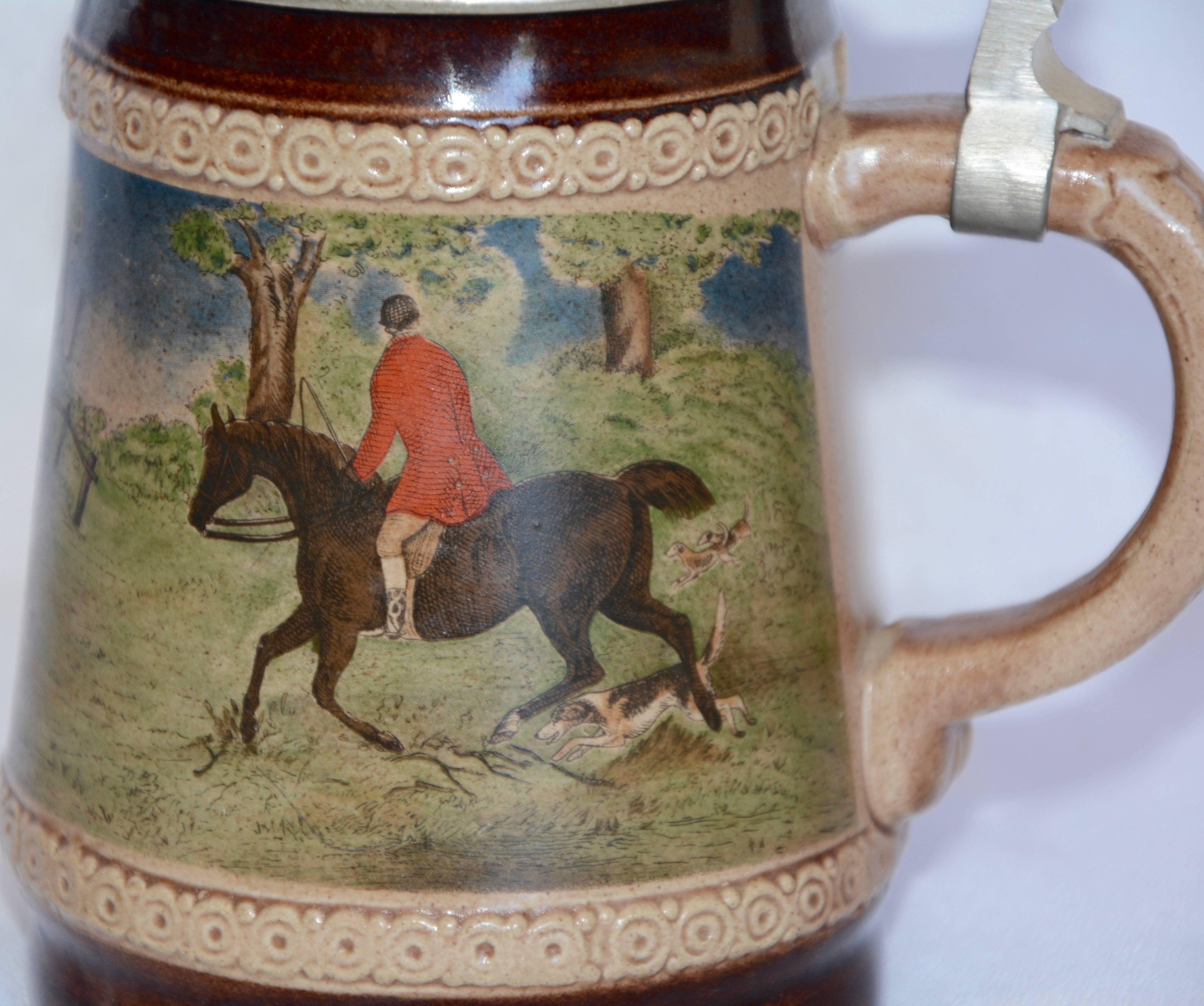 Auf diesem Bierkrug aus der Mitte des Jahrhunderts ist die Jagd mit den Hunden auf der Jagd nach dem Fuchs und den Reitern in Aktion. Es wurde von der 1880 gegründeten Firma Marzi und Remy in Deutschland hergestellt. Der Porzellankrug wurde