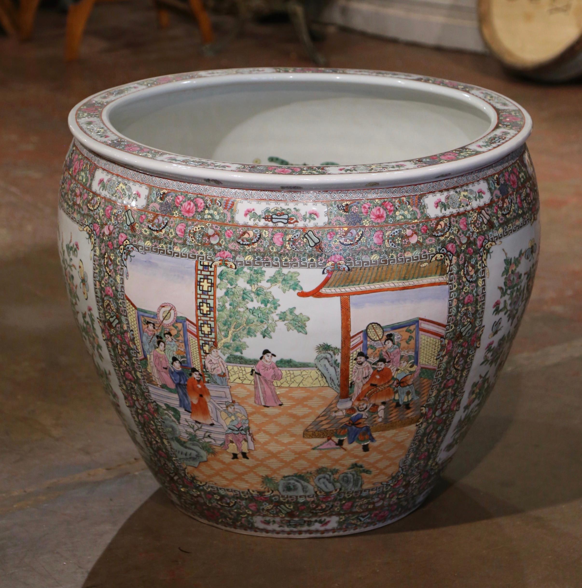 This massive and colorful vintage fishbowl was created in China, circa 1970. Round in shape, this elegant exotic porcelain planter features two large hand painted medallions with Chinese figural motifs and embellished with floral and leaf decor