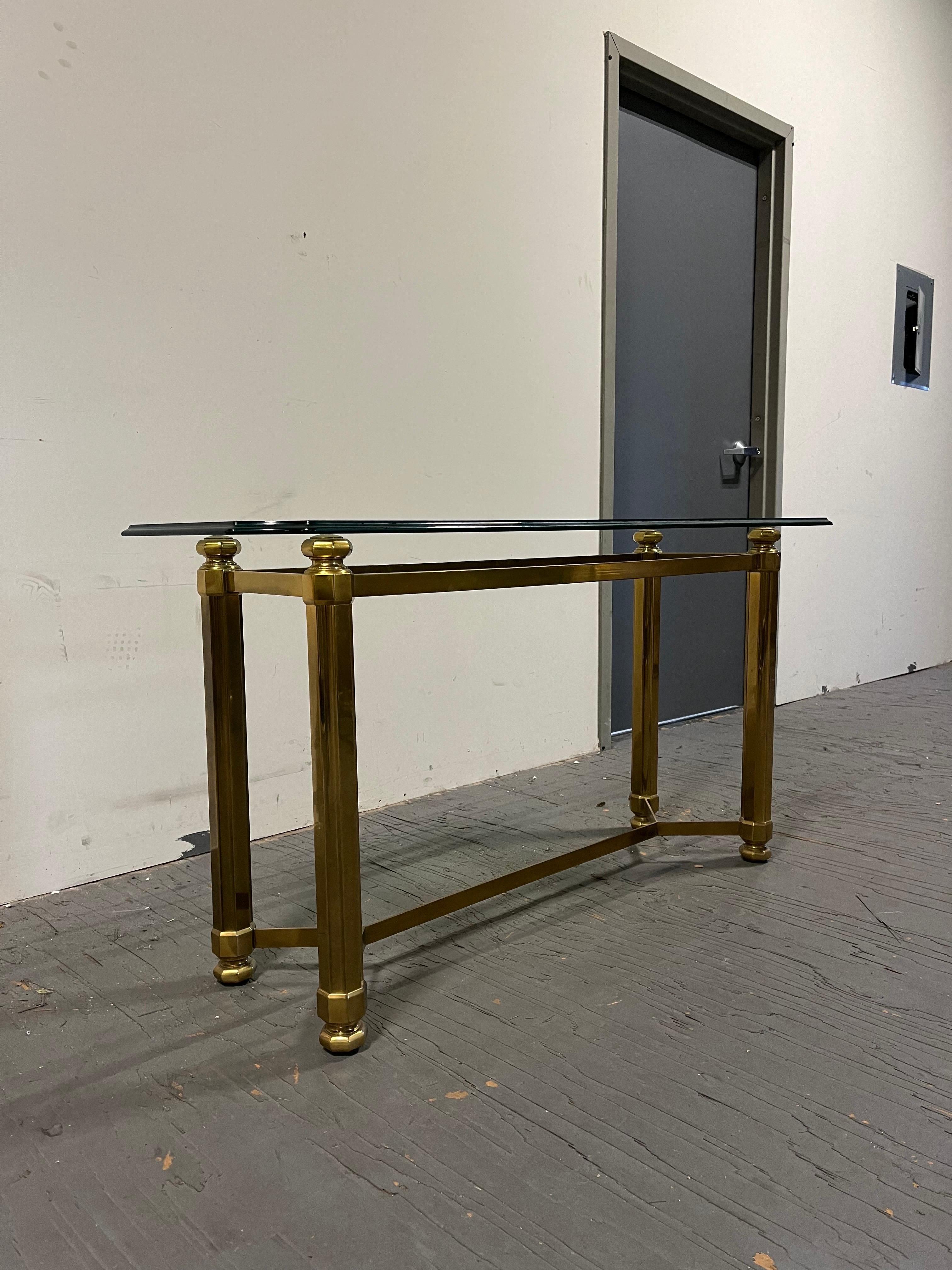 Beautiful classic brass console table with glass top. Regal columnar legs with substance and heft. Octagonal design with heavy final presence. OG beveld edge glass. 
Curbside to NYC/PHILLY $35O