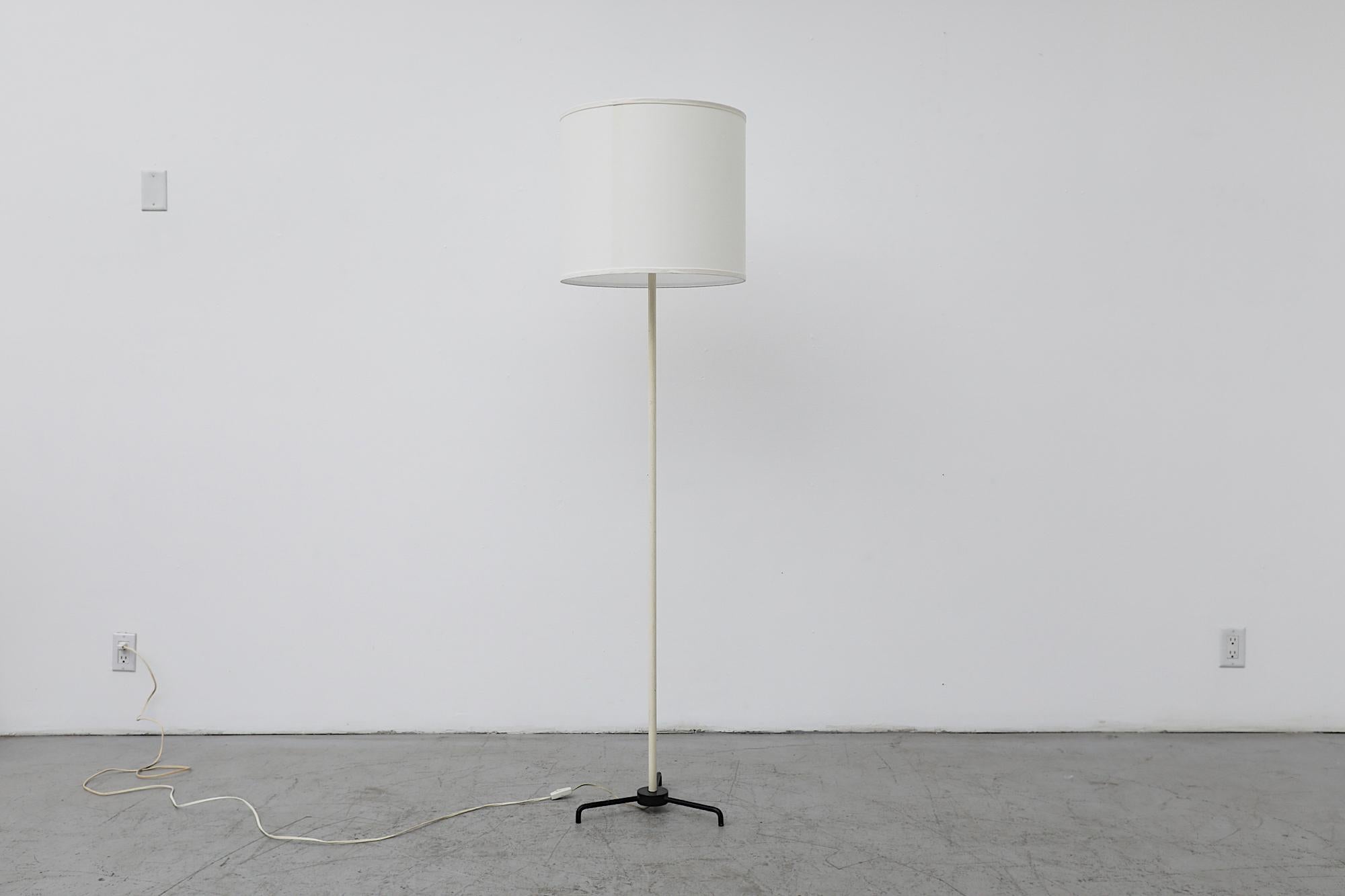 Mid-Century floor lamp with white enameled stem and black enameled Mategot Style tripod base. Newer white linen drum shade. In original condition with visible wear consistent with its age and use.