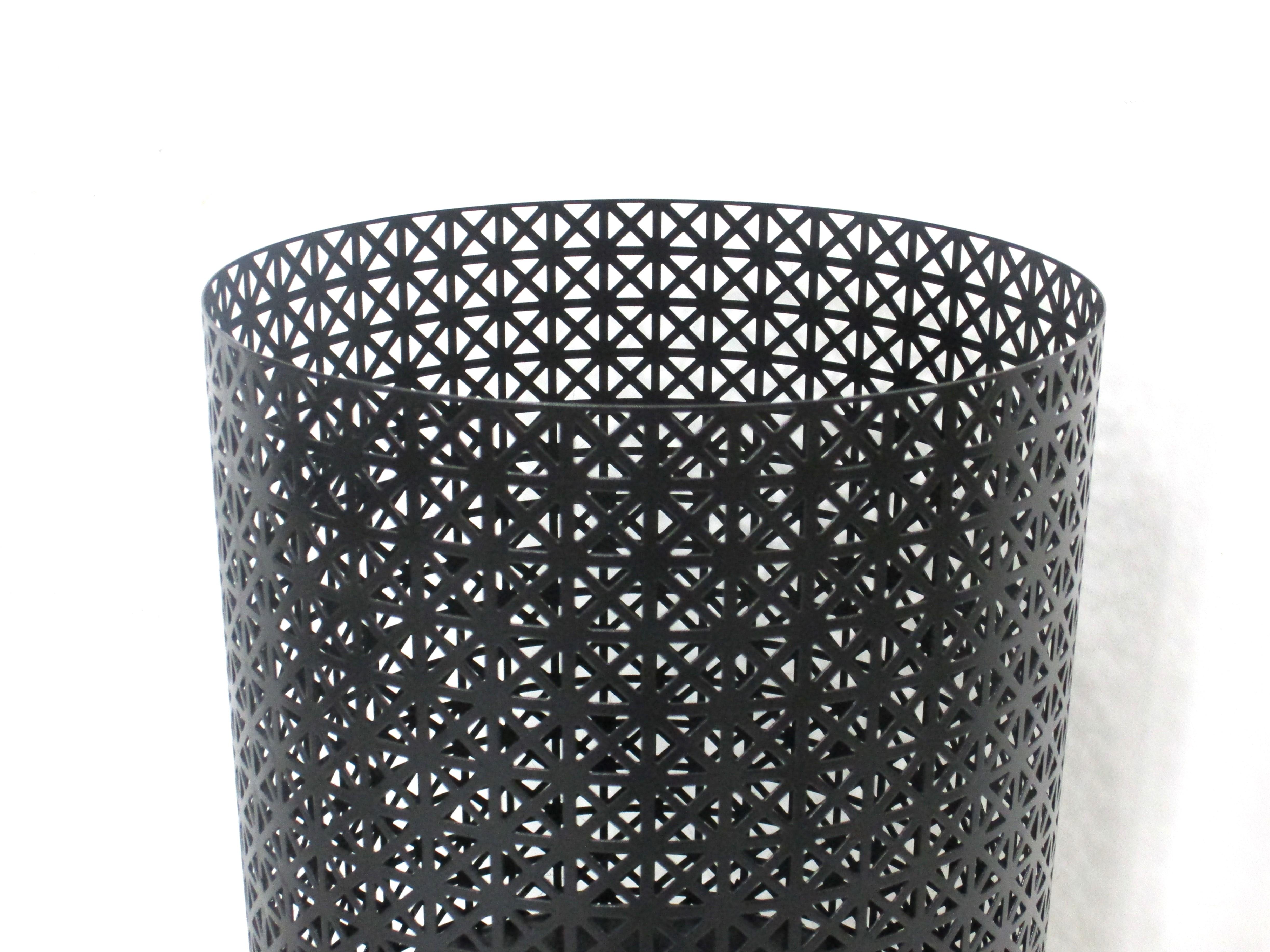 A satin black perforated metal trash basket with three legs having rubber capped ends to protect your floors . Very well crafted in the manner of French designer Mathieu Mategot a elegant form perfect for the home office ,dressing or bath area . 