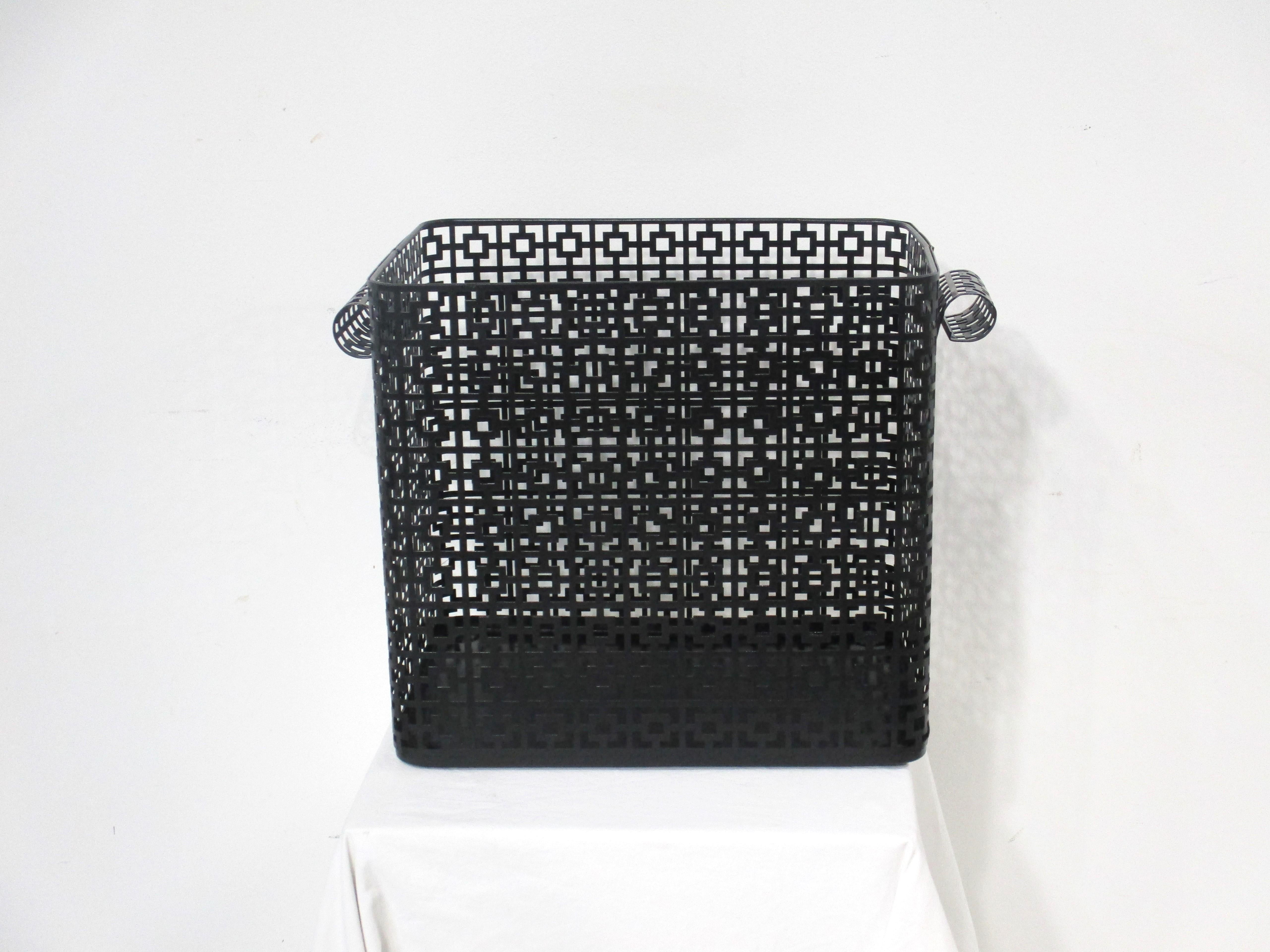 A satin black perforated metal trash basket that's very well crafted in the manner of French designer Mathieu Mategot . Having rolled handles to each end making for a elegant form perfect for the home office ,dressing or bath area . 