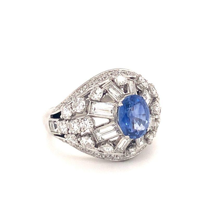 One mid-century Mauboussin sapphire and diamond dome ring centering one oval brilliant cut sapphire weighing approximately 2 ct. surrounded by 78 old European cut, baguette, single round cut and square cut diamonds totaling 3.25 ct. approximately.