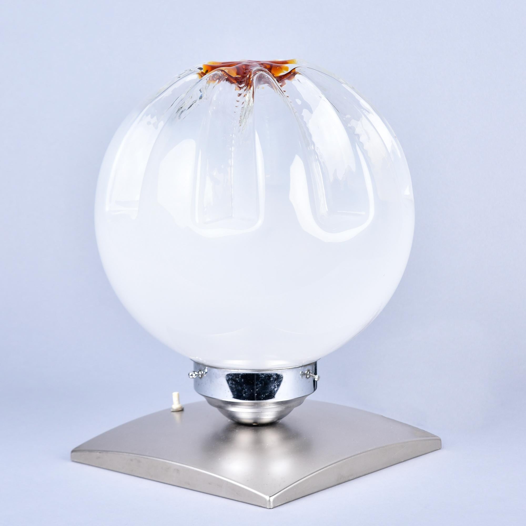 Found in Italy, this Mazzego table lamp dates from the 1970s. Single Mazzega Murano glass globe in one of their signature styles: White semi-opaque glass with indented, gathered sides and a rust colored accent at the top portion. Glass globe is set