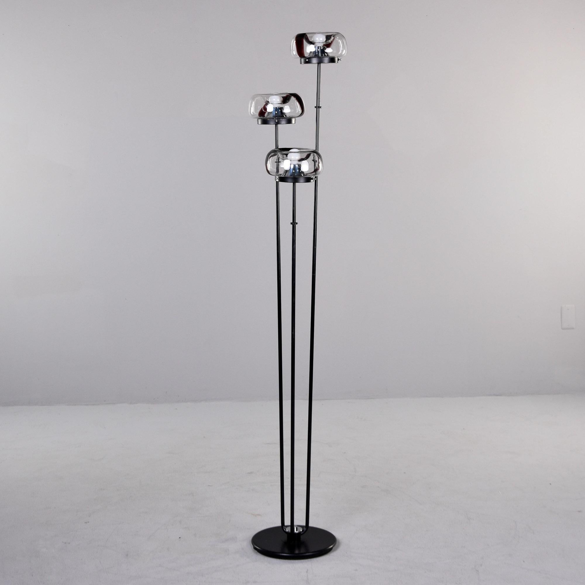 Found in Italy, this three light floor lamp by Mazzega dates from the 1970s. Black weighted metal base with three slender support rods topped with Mazzega Murano glass globes in clear with brown swirls. New wiring for US electrical standards and new