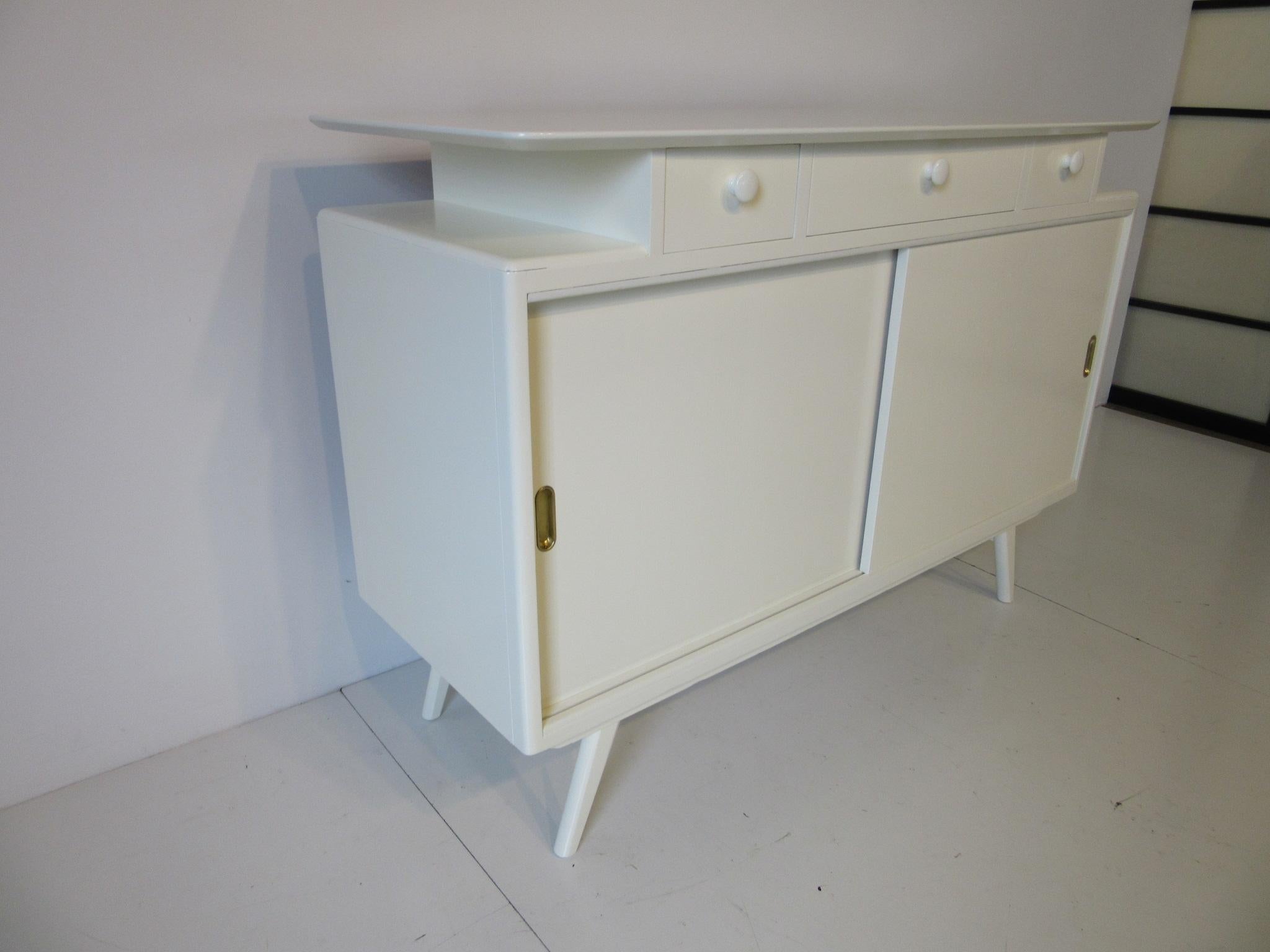 A Mid Century cabinet which makes the perfect baby changing cabinet or just a TV cabinet , three smaller drawers to the top and two sliding doors below with brass pulls a shelve and storage, manufactured by Avalon Yatton .