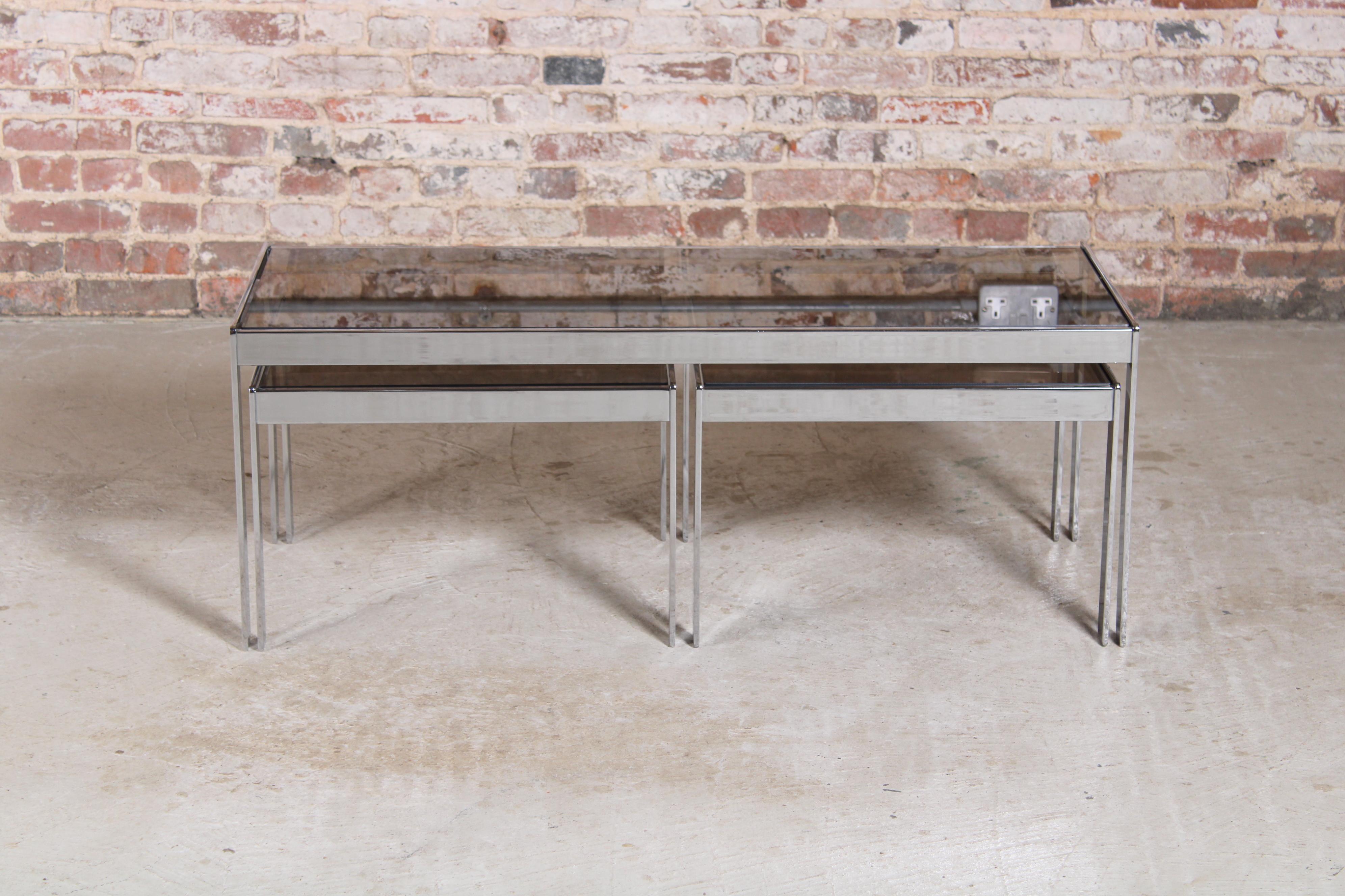 Mid Century Merrow Associates chrome and smoked glass nest of tables, circa 1970s. Minor scratches on glass.

Dimensions:
Large table: 114 W x 46 D x 43 H cm
Small table: 53.5 W x 46 D x 36 H cm.