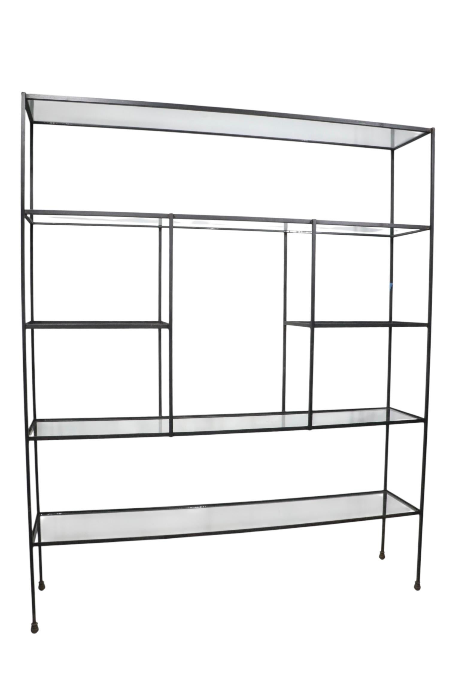 Large Mid Century display rack, constructed of solid squared stock iron, with drop in glass shelves, and cast iron boot feet. The shelf features six shelves,  creating ample storage, and display space. This example is in very good, clean, and ready