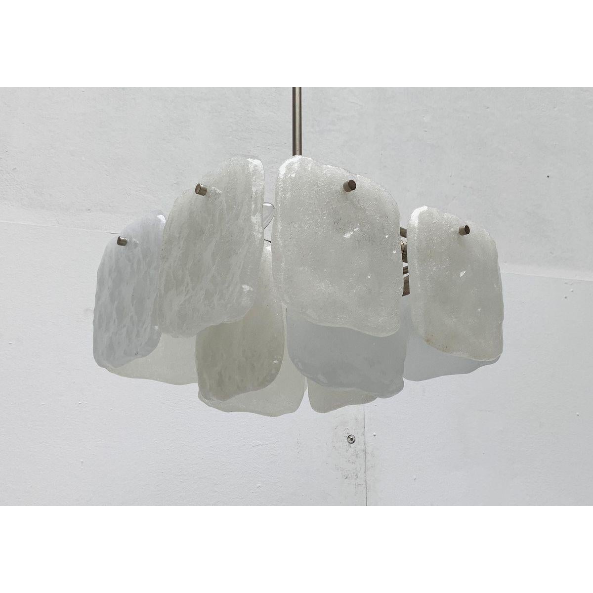 Raro lampadario in vetro del rinomato produttore Kalmar.

Imponente lampadario con elementi in vetro annidati. Nella sua linearità, questo design mostra un linguaggio formale piuttosto funzionale. Da un albero centrale, le barre di metallo escono ad