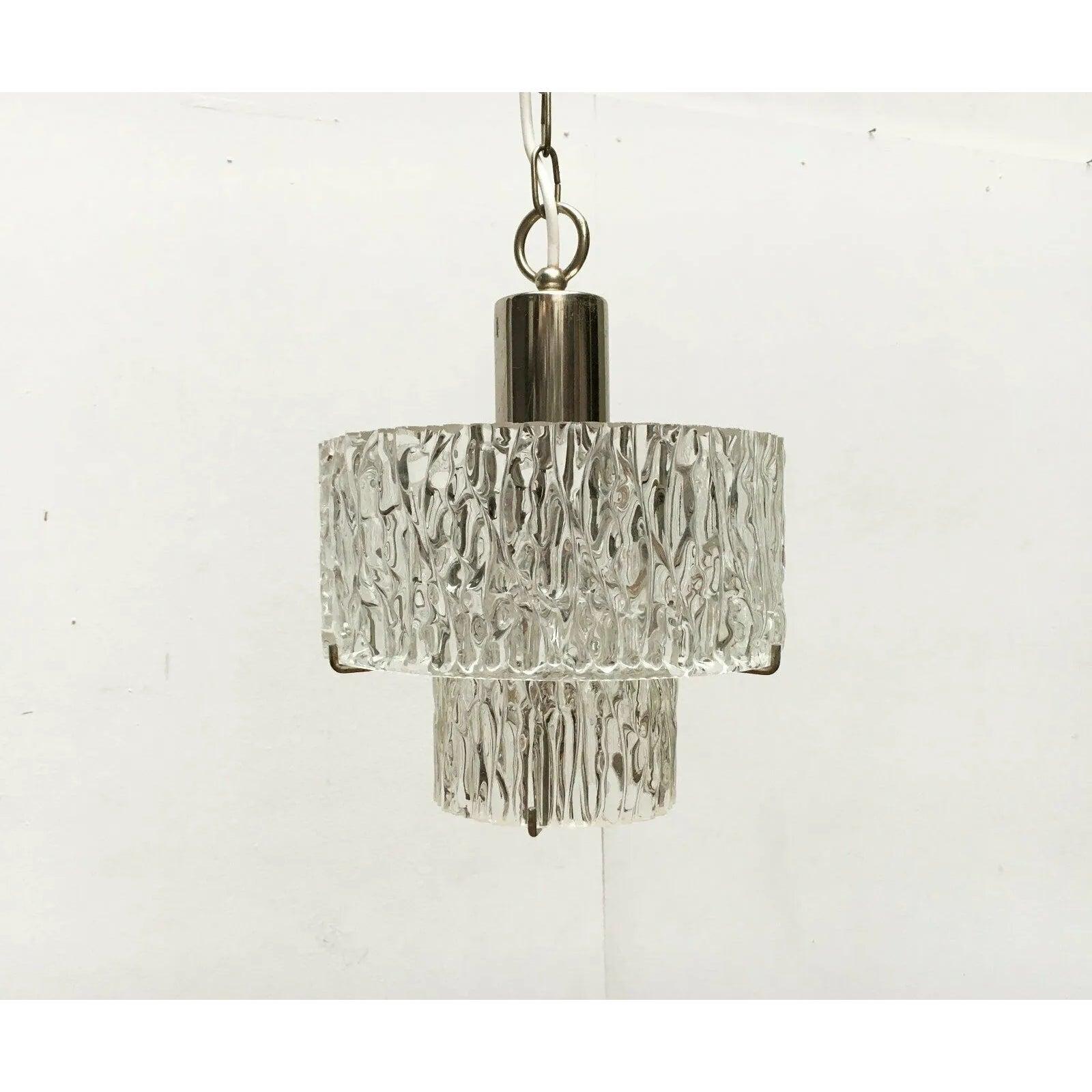 Imposante lampe suspendue du milieu du siècle avec verre structuré.

Deux anneaux en verre épais et structuré, disposés sur deux niveaux, servent de réflecteurs. Les verres sont posés sur des supports métalliques. Le noyau est chromé et reflète les