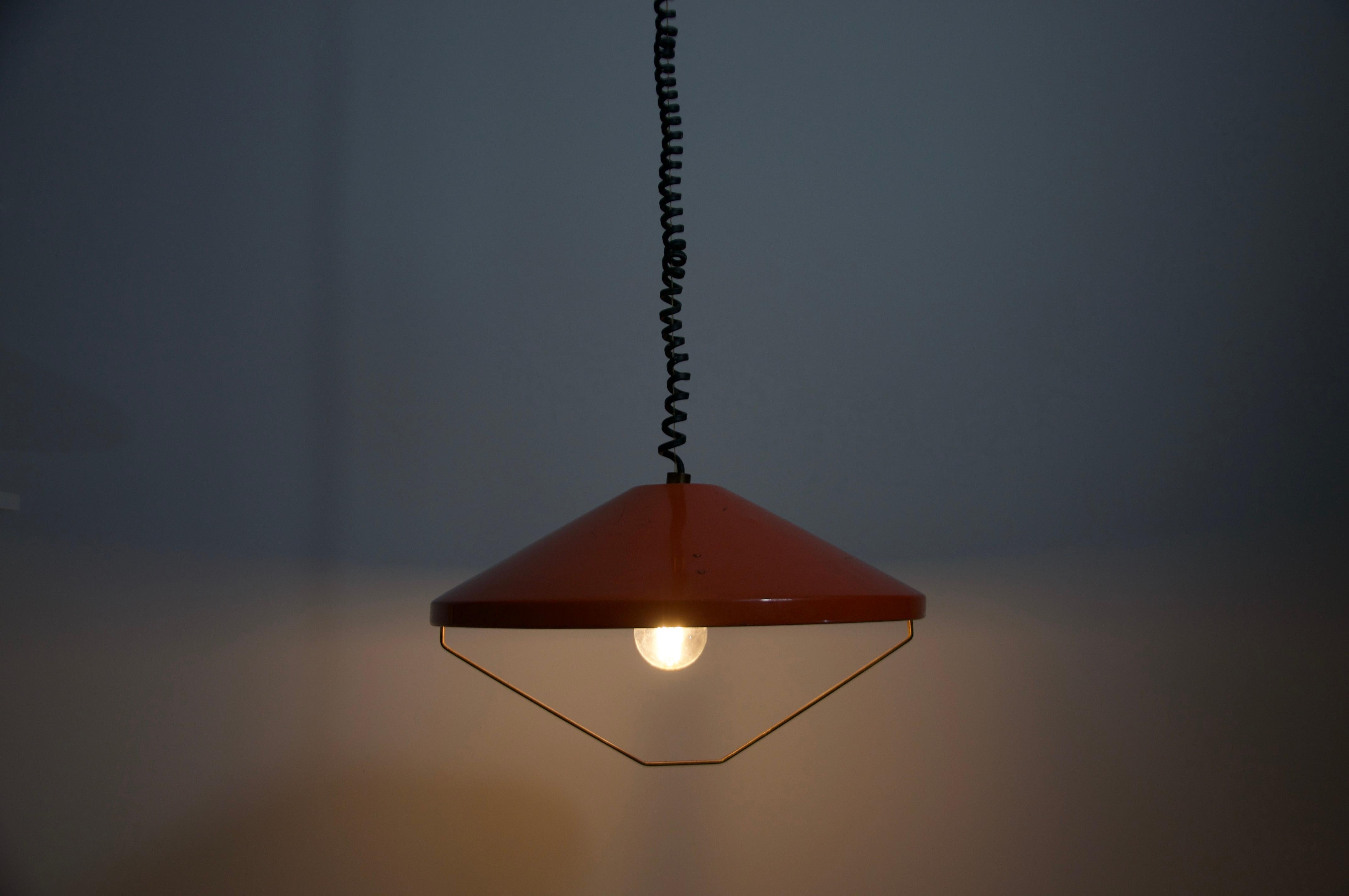 This vintage pendant lamp by Stilnovo is a stunning example of Italian mid-century design from the 1960s. The lamp features an orange metal shade with clean, geometric lines and a minimalist aesthetic typical of the era. Its industrial yet elegant