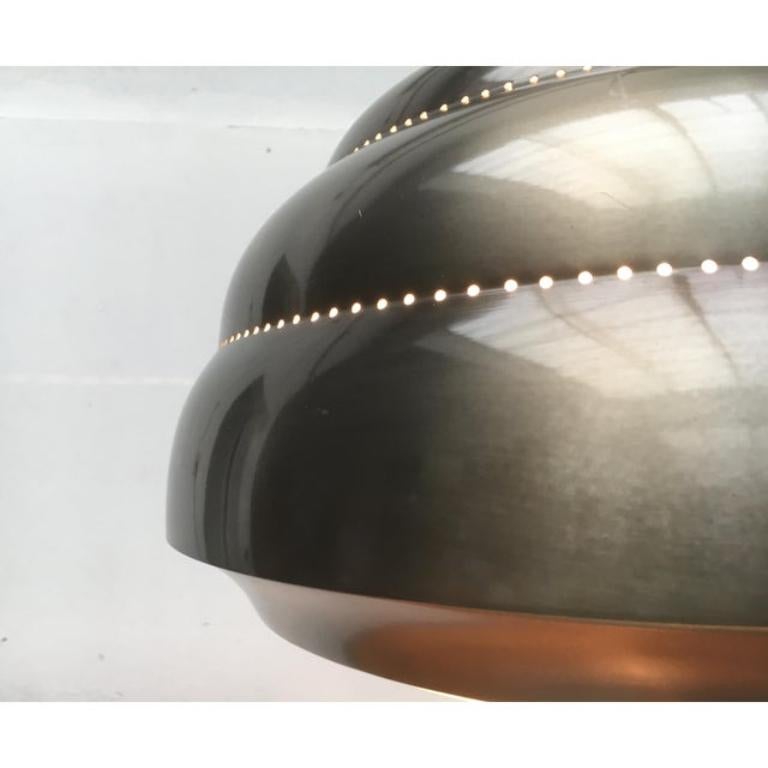 Imponente lampada a sospensione di metà secolo proveniente dall'Italia.

Un design classico ma moderno. Le curve convesse del paralume superiore in metallo sono caratterizzate da una perforazione. Le sottili linee di perforazione si evidenziano