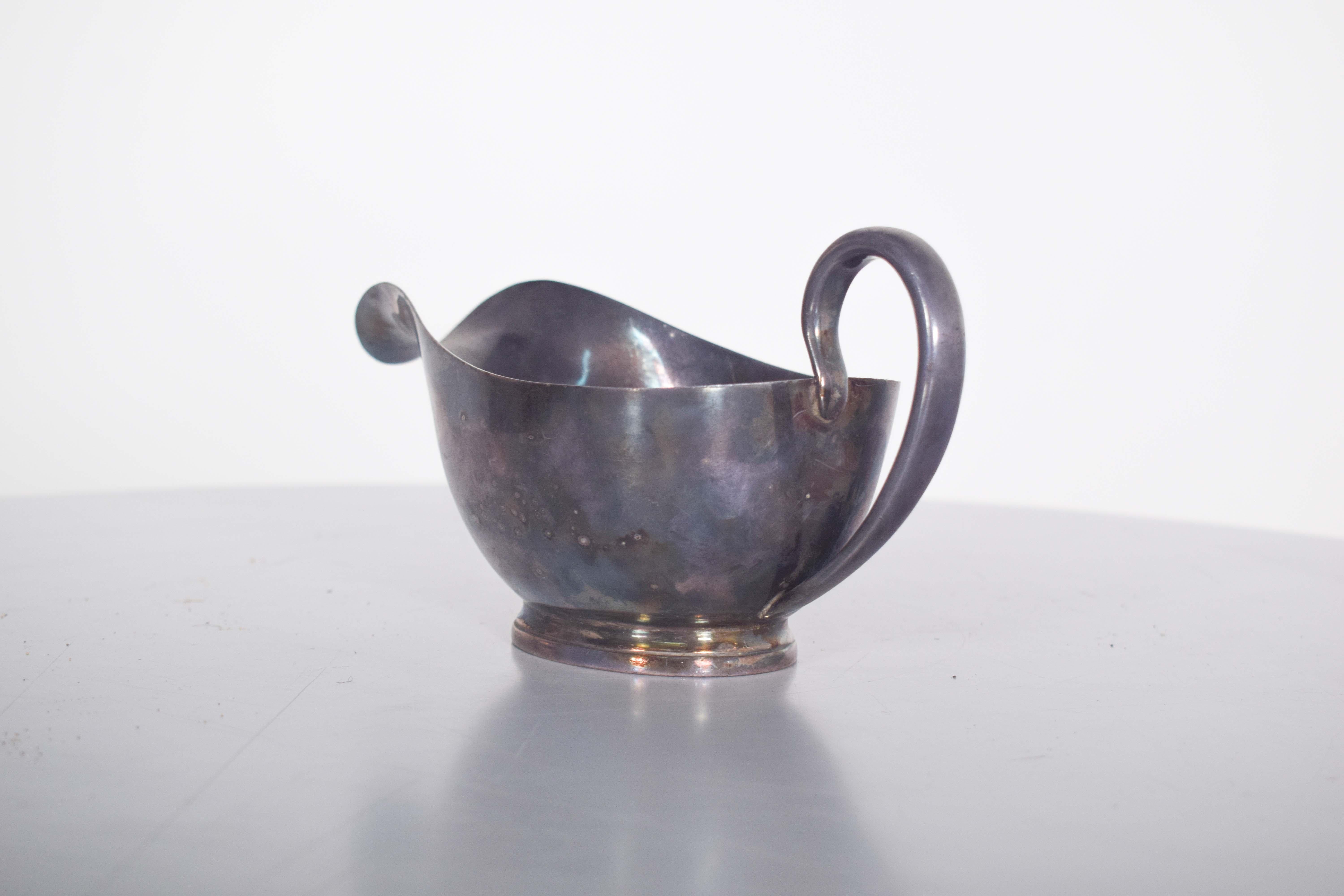 Saucière en métal. Avec une base ovale, qui apporte une touche de distinction et de douceur à son design. La forme élégante de la base est complétée par la poignée, qui s'incurve délicatement, offrant une prise en main confortable tout en donnant à