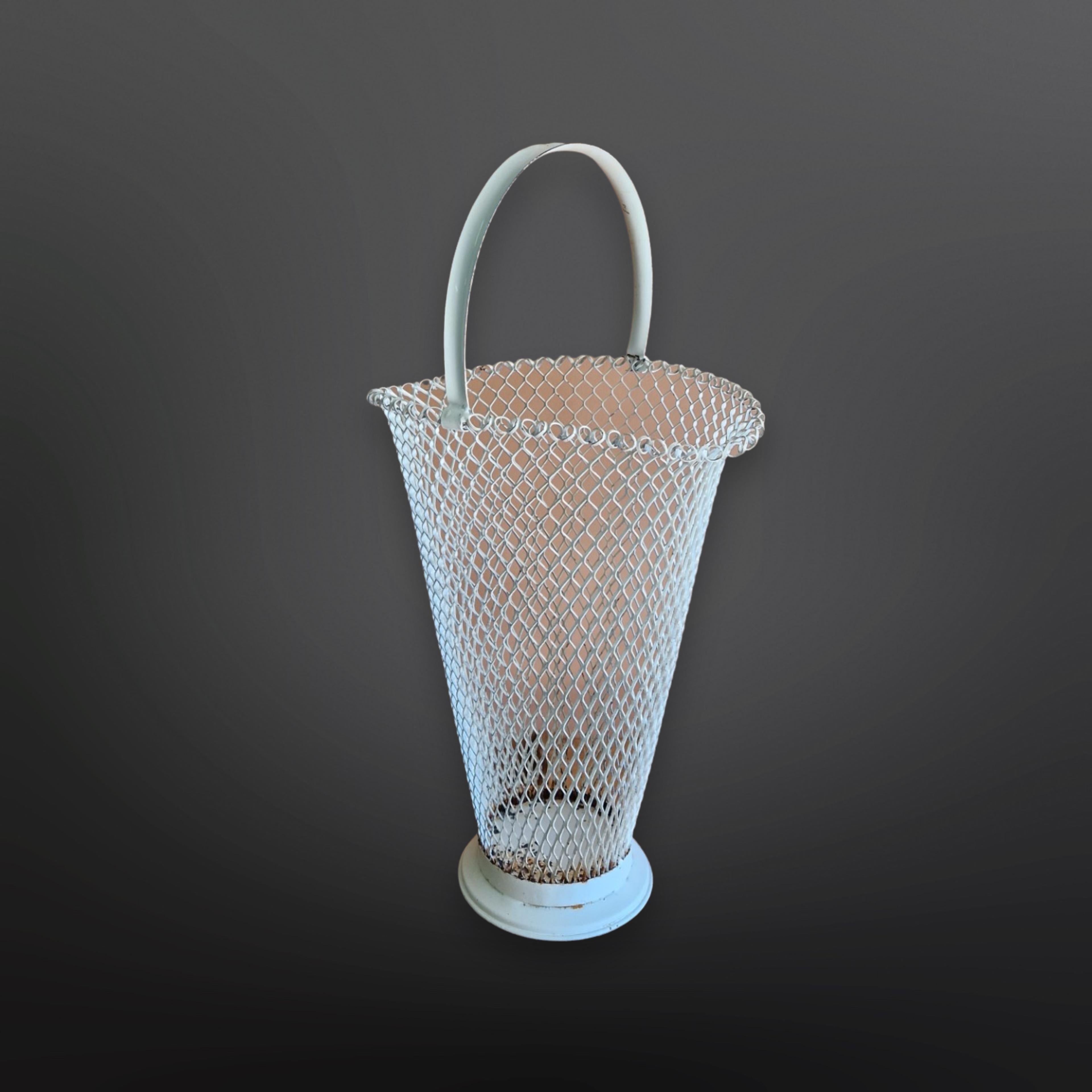 Original mid-century umbrella stand in the manner of Mathieu Mategot. It is made from metal mesh. The white paint is original. Besides an umbrella stand it is also suitable as a waste paper basket. 
It has a large metal handle and a heavy base