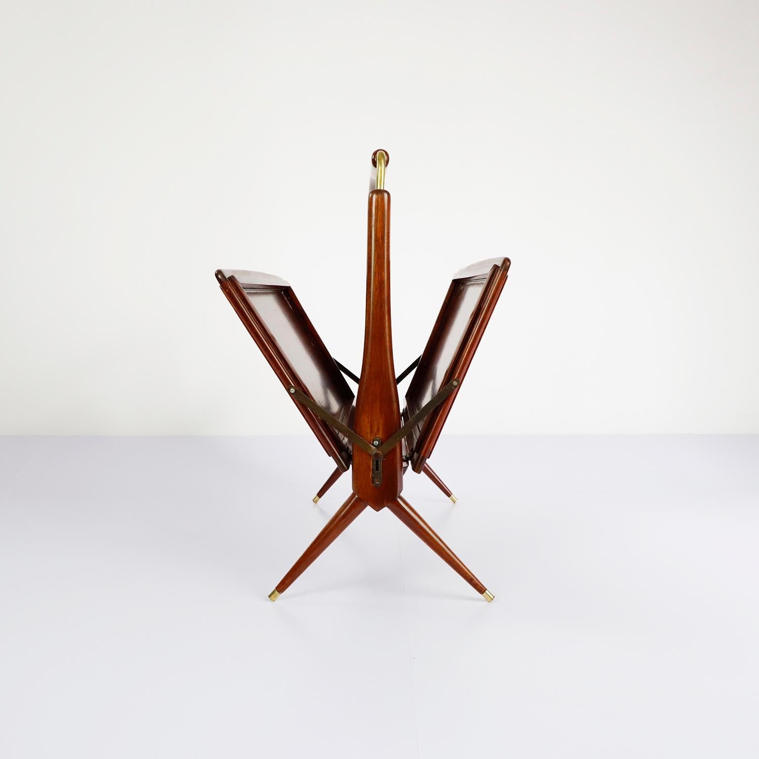 We offer this folding magazine rack in mahogany wood and brass details, circa 1950.