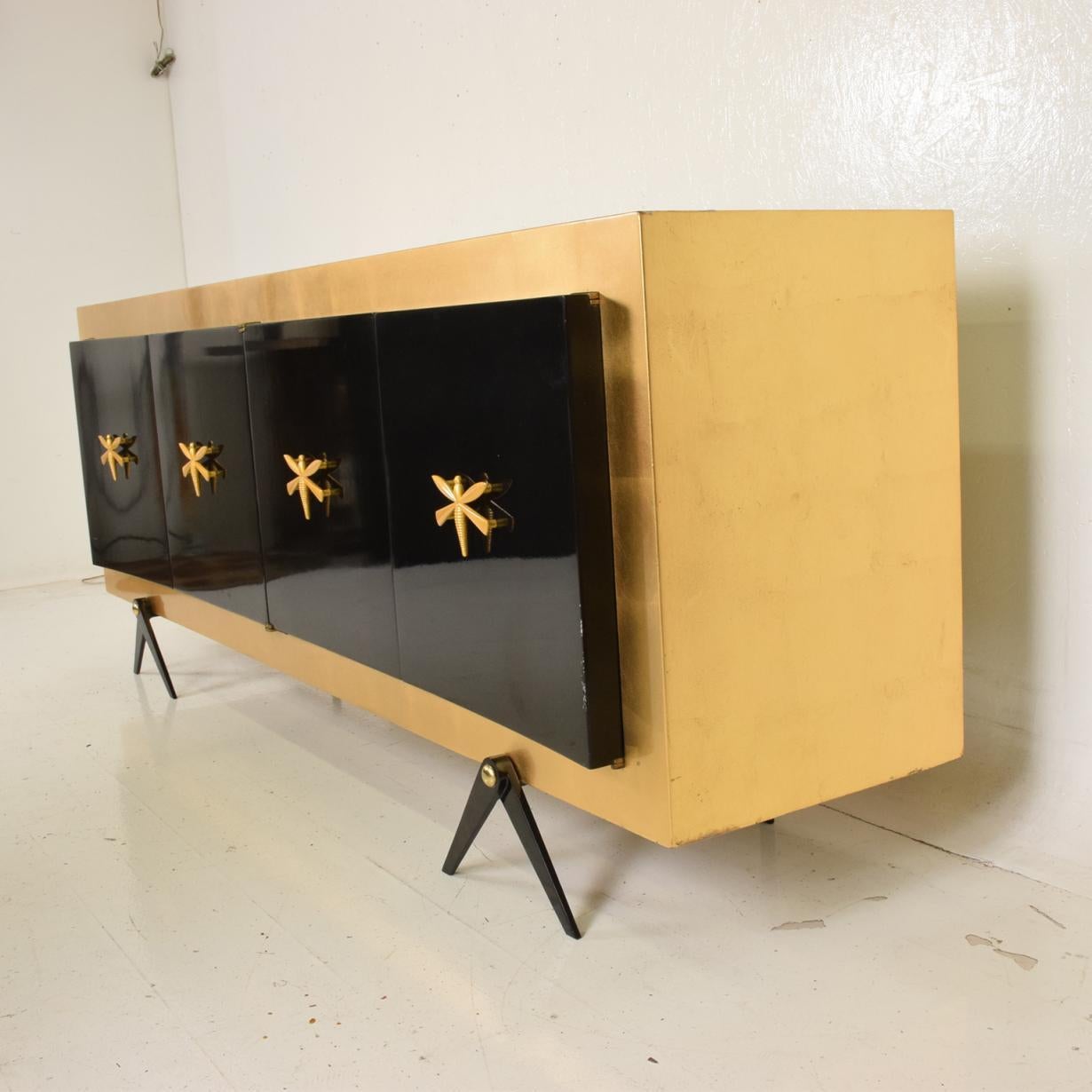 For your consideration, a midcentury Mexican Modernist stunning credenza after Arturo Pani.


A beautifully restored condition in gold leaf and black lacquer. 


Bronze butterfly pull handles decorate the four doors. Open storage with no drawers.