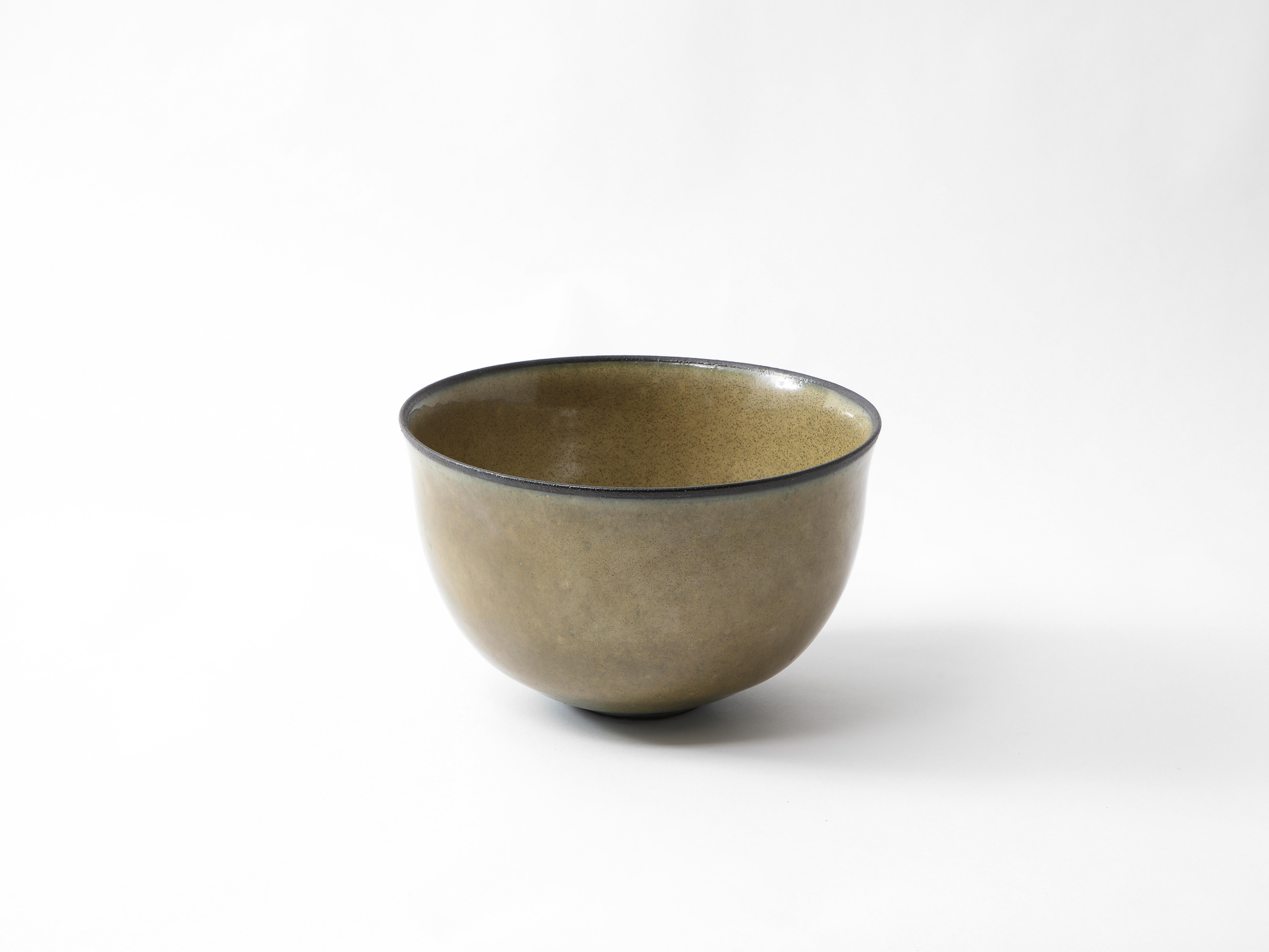 Mid-century circular ceramic bowl in dark mustard with granular dot detail. The very top is outlined in a thin line of black glaze. Signed M Breum underneath.