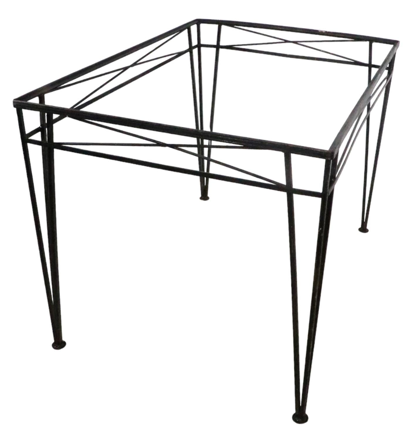 Chic architectural dining table constructed of wrought iron, attributed to Salterini, in the style of Woodard Furniture. This example is structurally sound and sturdy, the finish shows cosmetic wear, normal and consistent with age. The table is