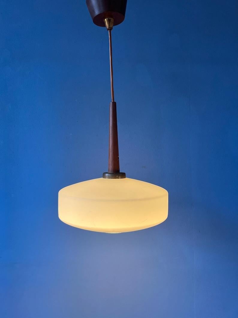 Vintage Danish style milk glass pendant light by Louis Kalff for Philips. The lamp has an UFO-shaped glass shade and a teak wood top cap. The lamp requires an E27/26 (standard) lightbulb.

Additional information:
Materials: Glass, wood
Period: