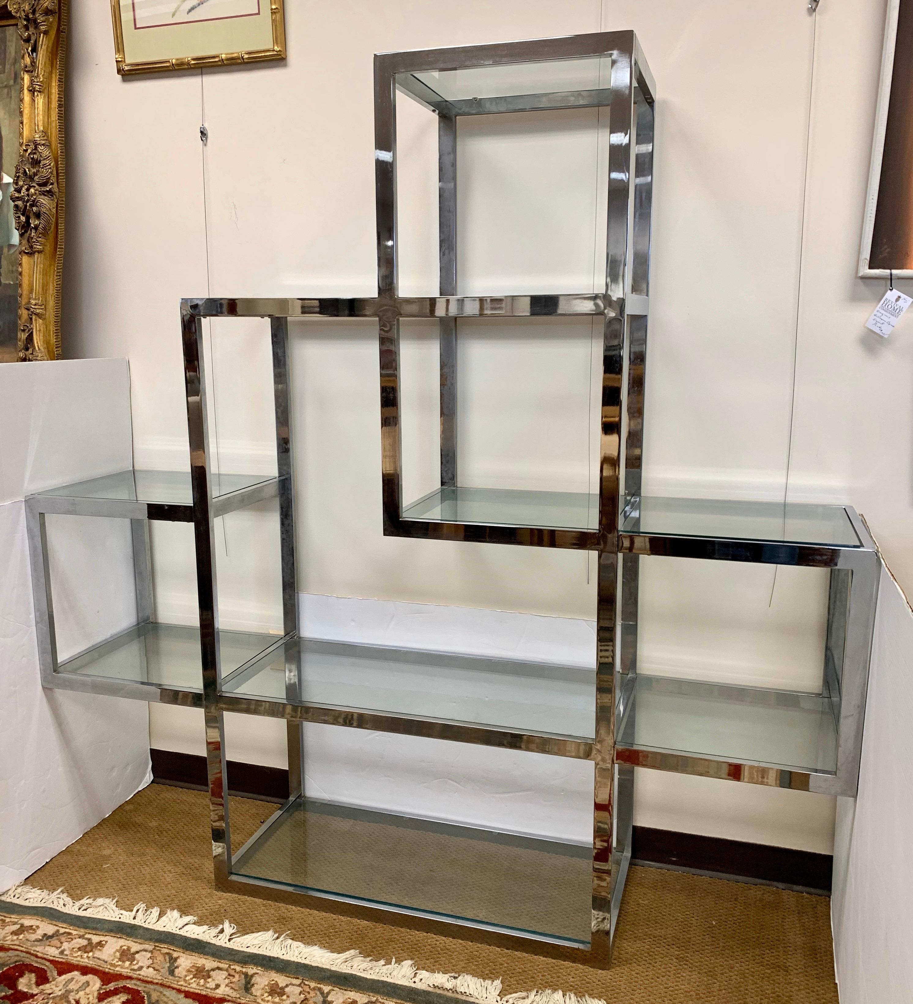 Measuring six feet at its widest point by six feet tall, this étagère has great lines and scale. This iconic étagère has custom fit glass shelves and thick chrome frame, not thin like recent reproductions. This is in the style of Milo Baughman.